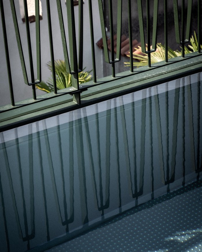 Reflection of metal railing on the water surface of a small pool