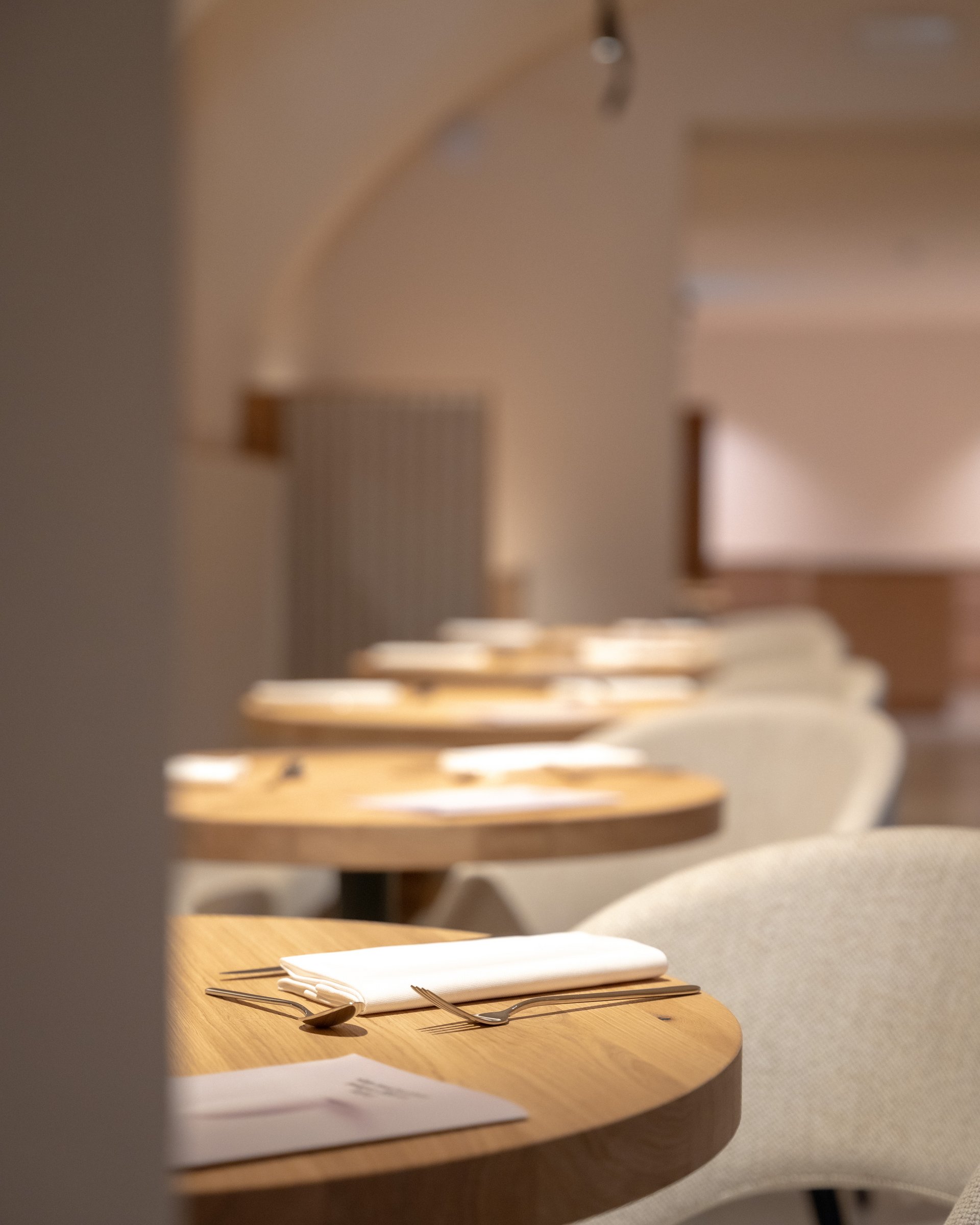 Elegante, gedeckte Tische mit Besteck und Servietten in modernem Restaurant