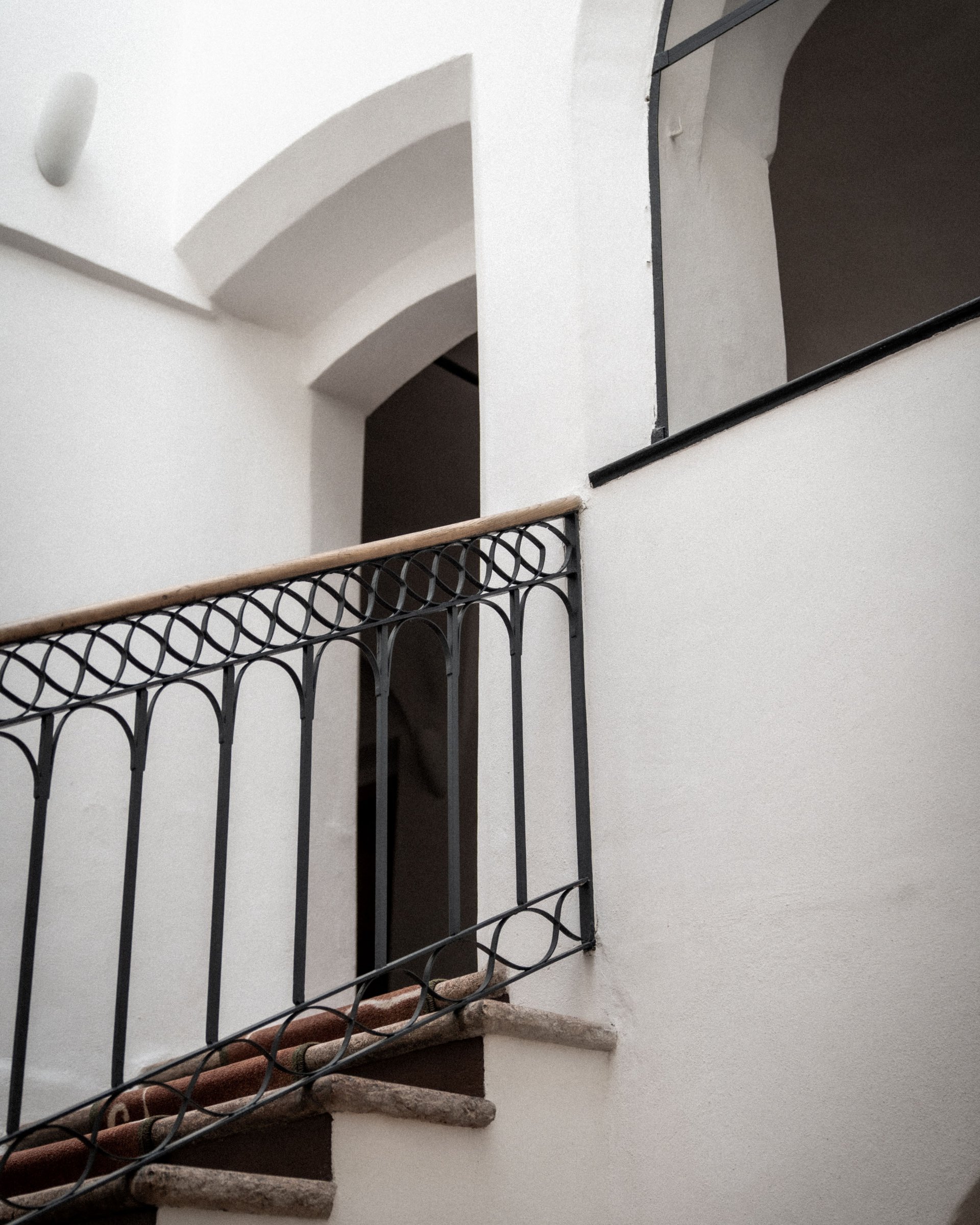 Indoor staircase with wrought iron railing and wooden handrail
