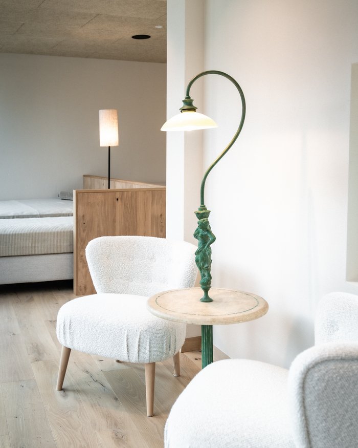 Bright room with two white armchairs, small table, and a lamp