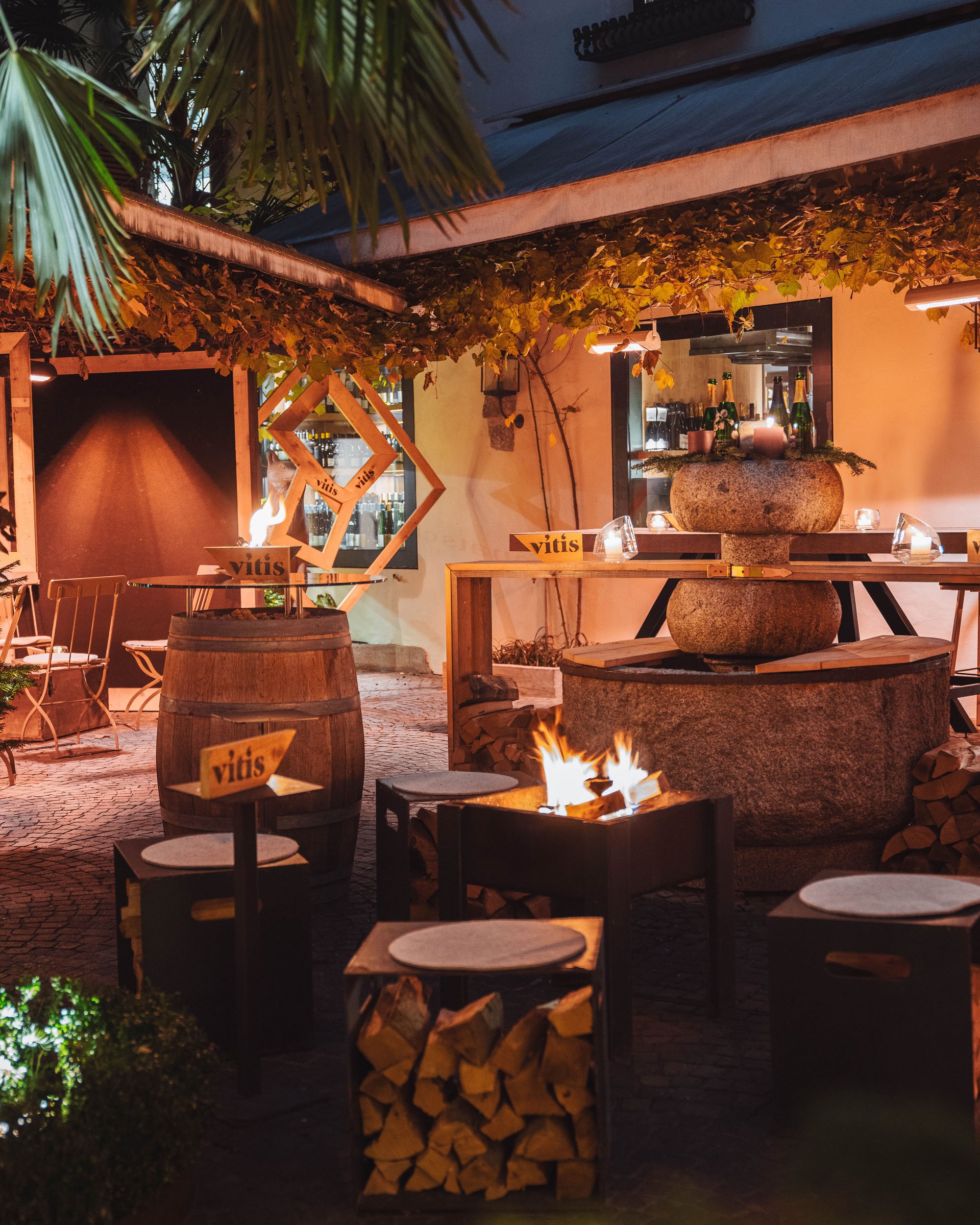 Cozy outdoor bar with fire pit and stacked firewood at night