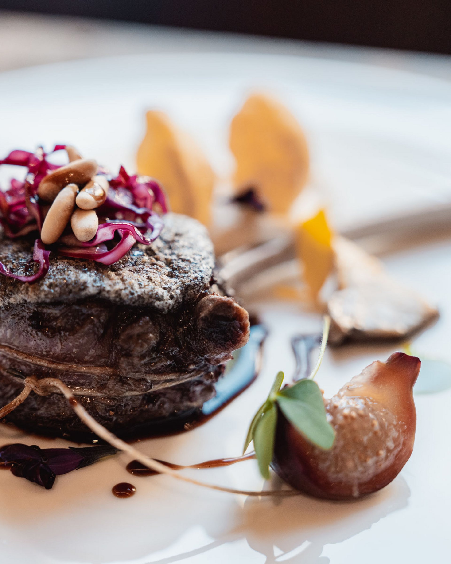 Gourmet steak with pine nuts and red cabbage artfully plated on a white dish