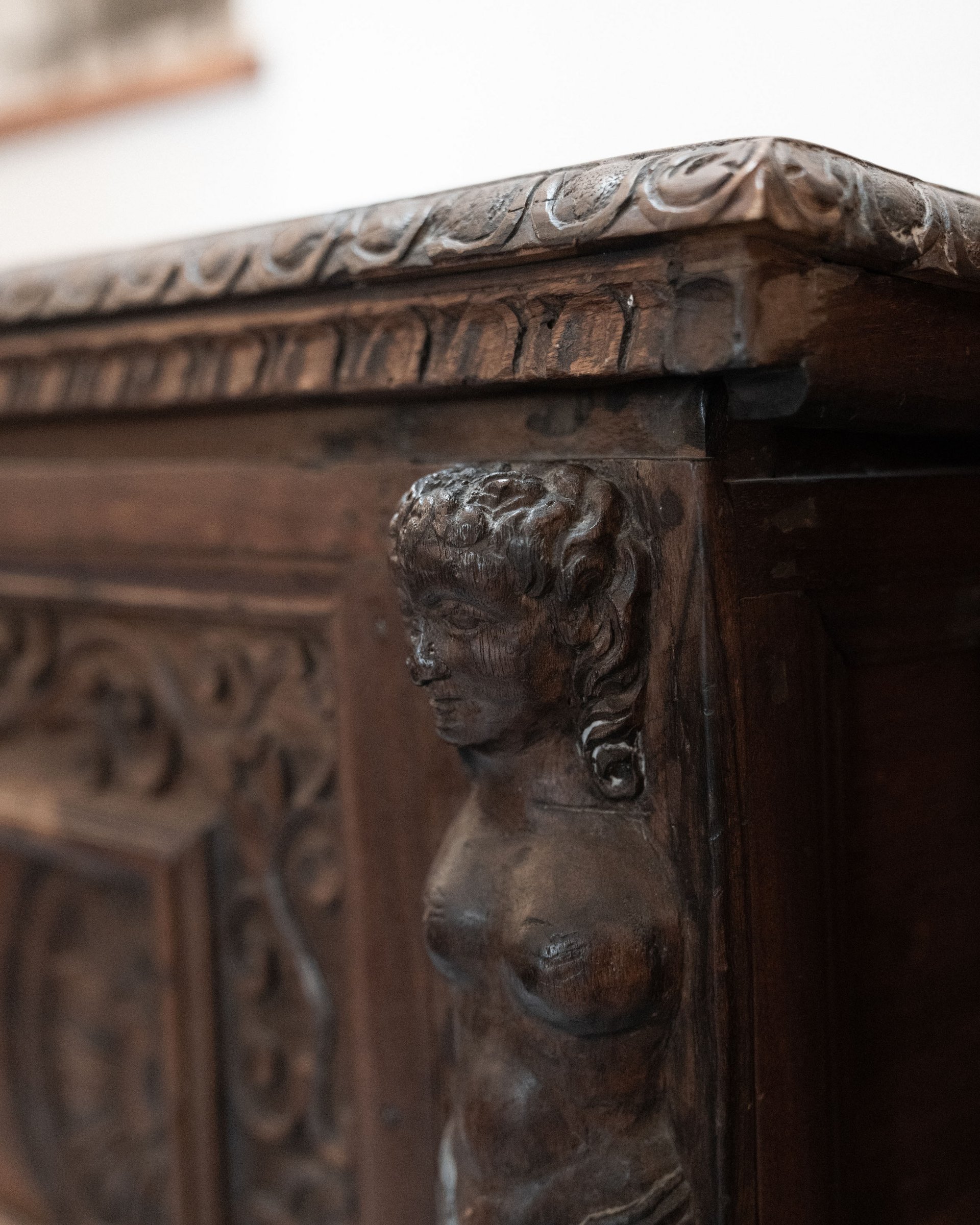 Close-up of antique wooden cabinet with carved female figure decoration