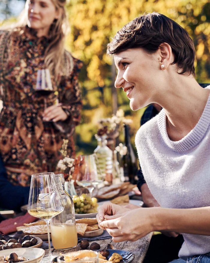 Freunde genießen Wein und Snacks bei einem Treffen im Freien im herbstlichen Weinberg.