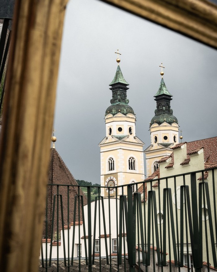 Church tower with two spires and clock seen through a golden frame