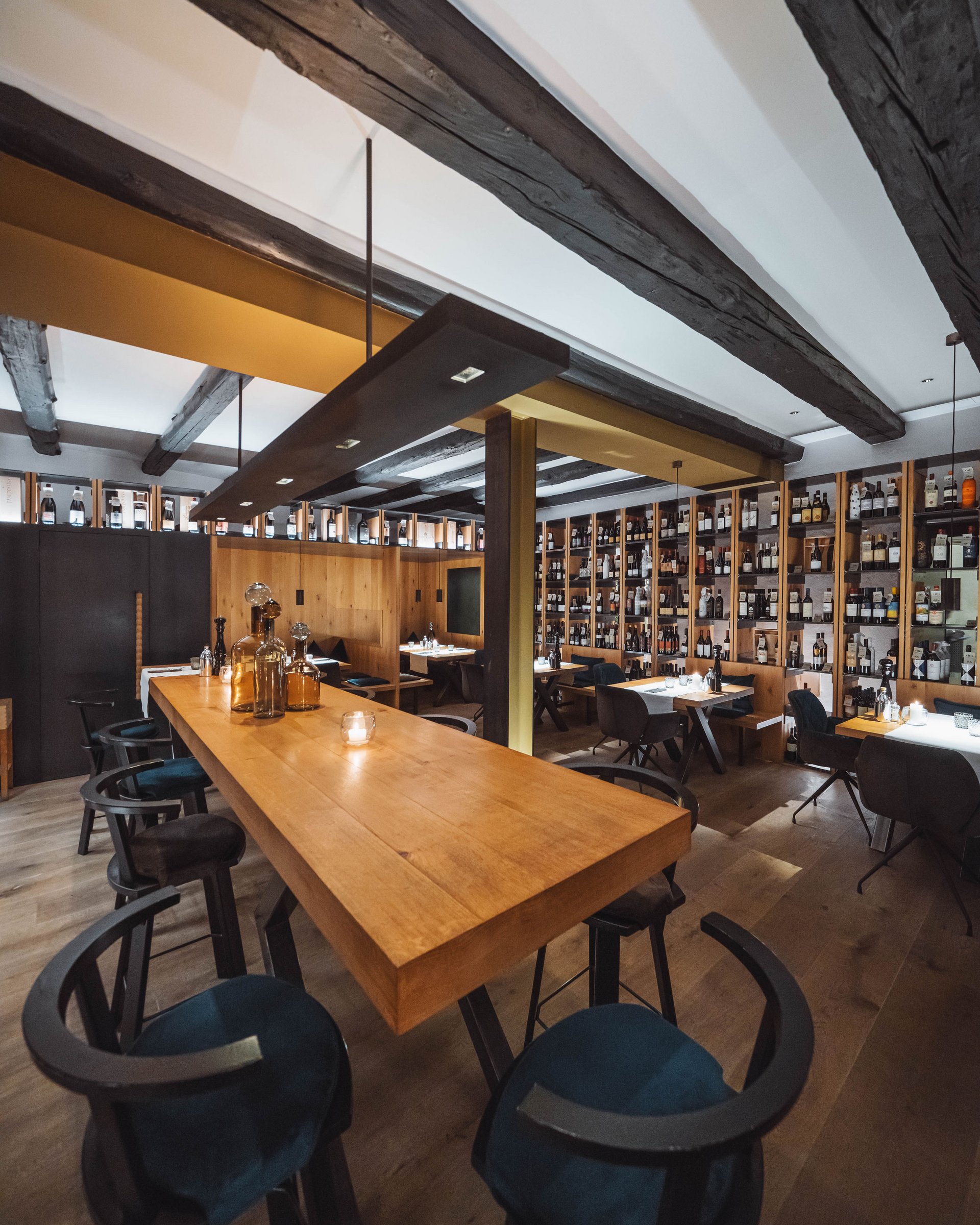 Modern restaurant with wooden tables and walls full of wine bottles