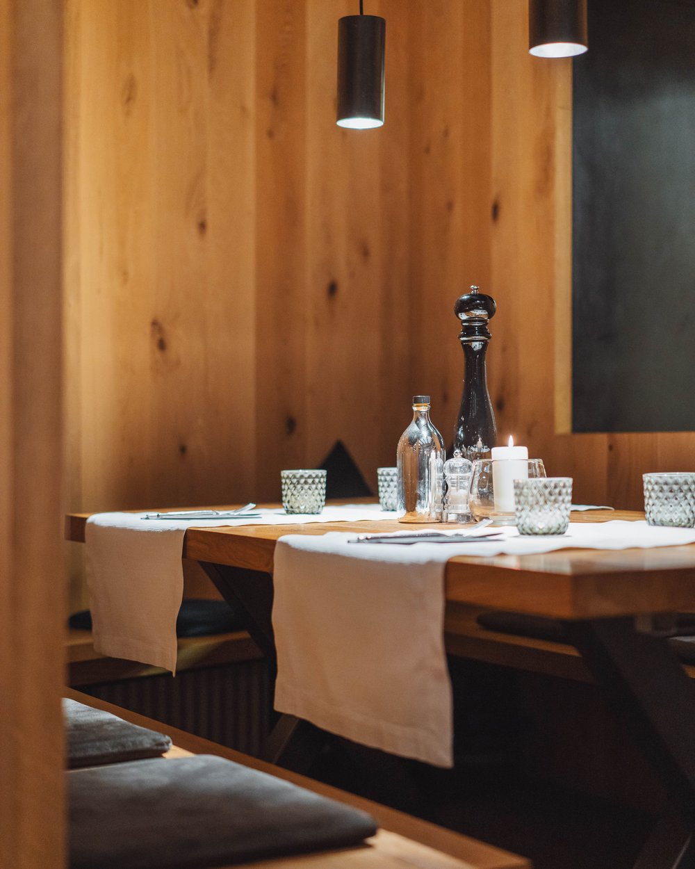 Cozy wooden table with placemats, candle, and spices in a restaurant