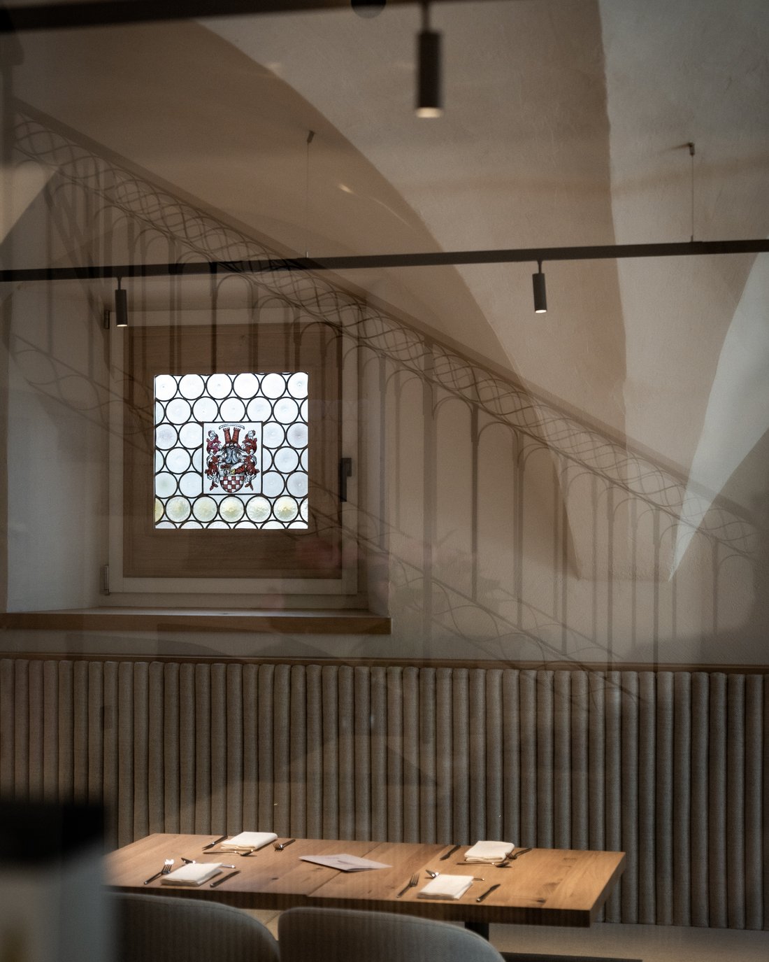 Gemütliches Restaurant mit Holztisch und verziertem Fenster mit Wappen