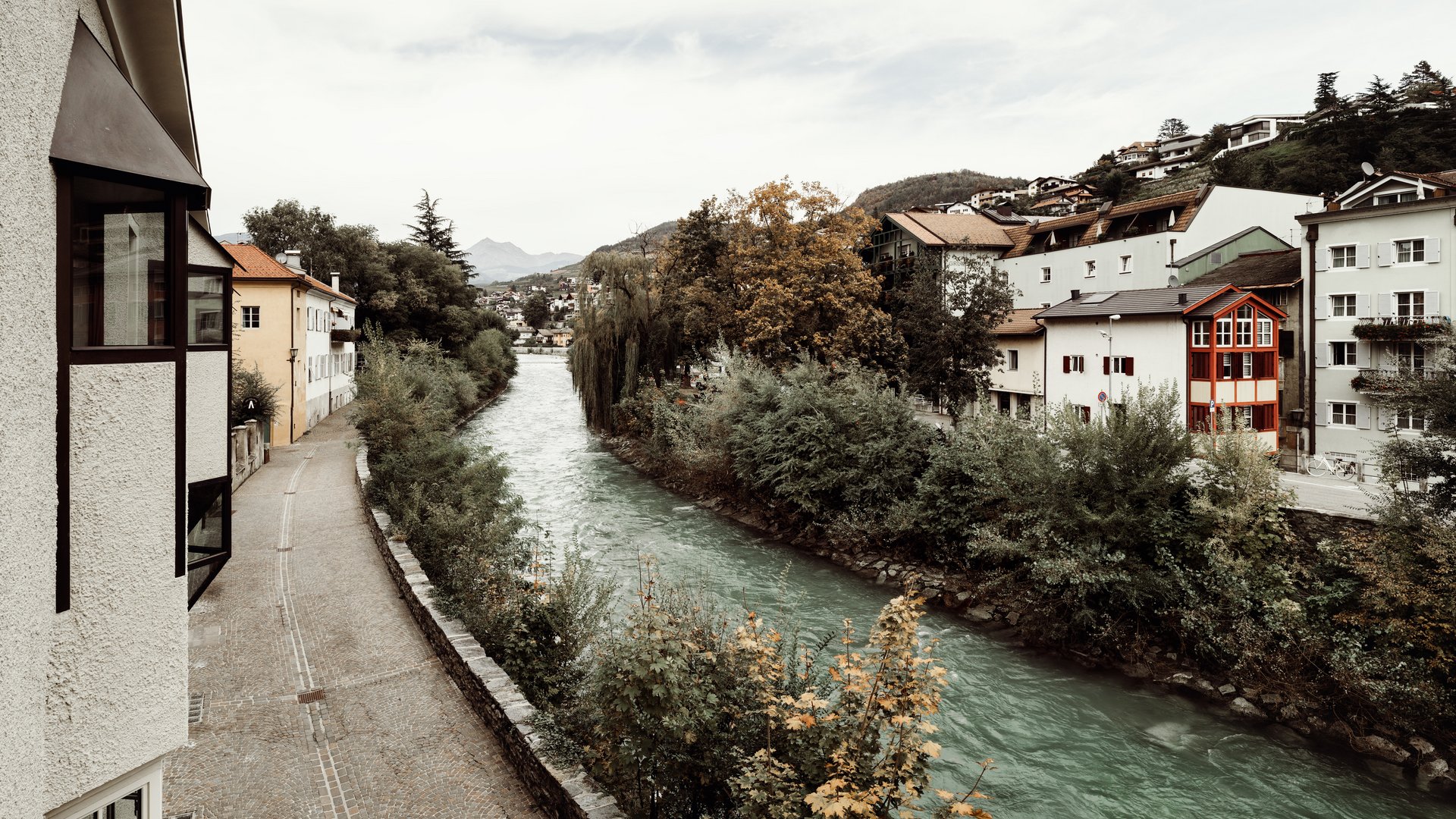 Fluss mit Bäumen und Häusern an beiden Ufern in einer kleinen Stadt