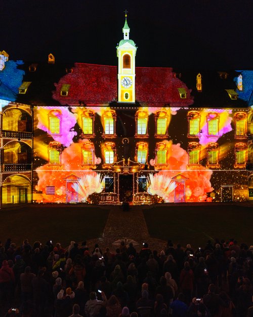 Lichtshow an einem historischen Gebäude mit Zuschauer bei Nacht