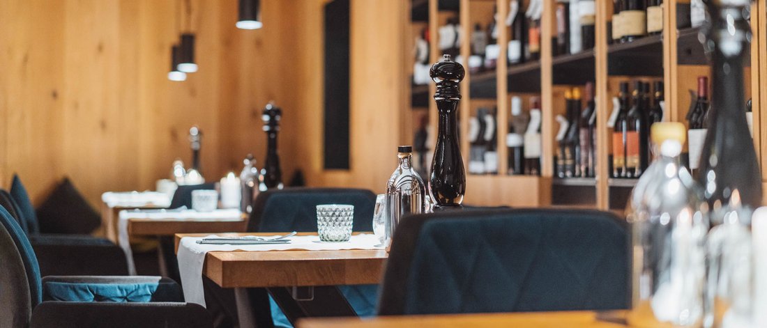 Gemütliches Restaurant mit Weinregalen und eingedeckten Holztischen
