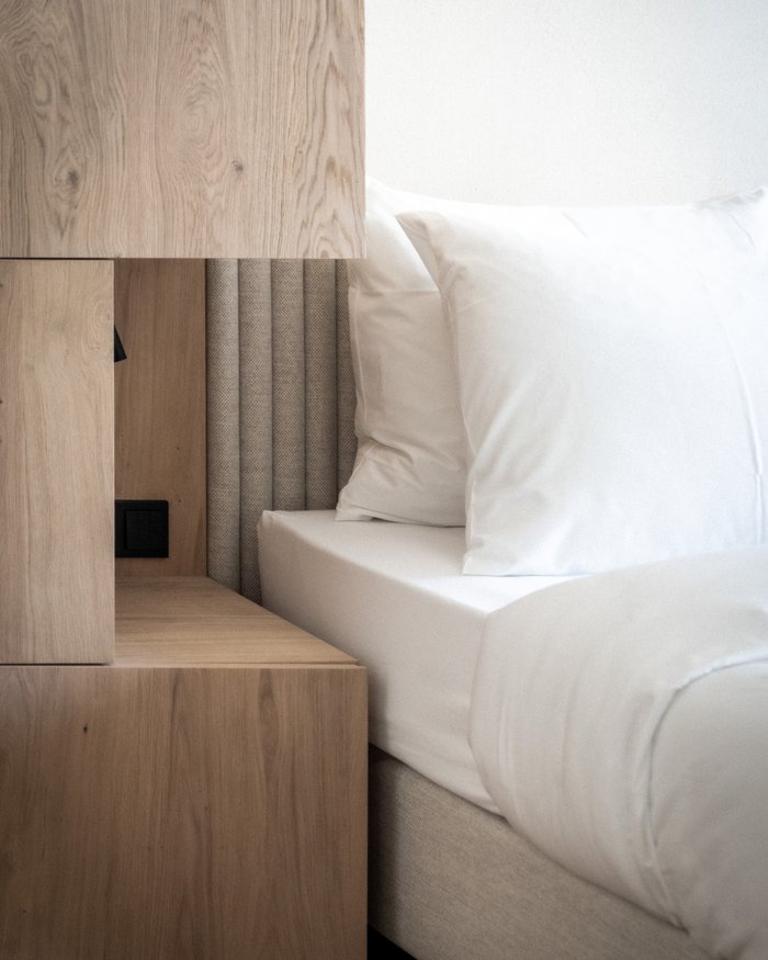Holz-Nachttisch neben weißem Bett mit Kopfkissen in modernem Schlafzimmer