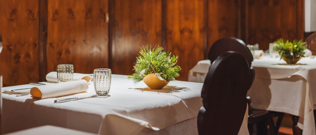 Restauranttische mit weißen Tischdecken und grünen Pflanzen in Holzinterieur
