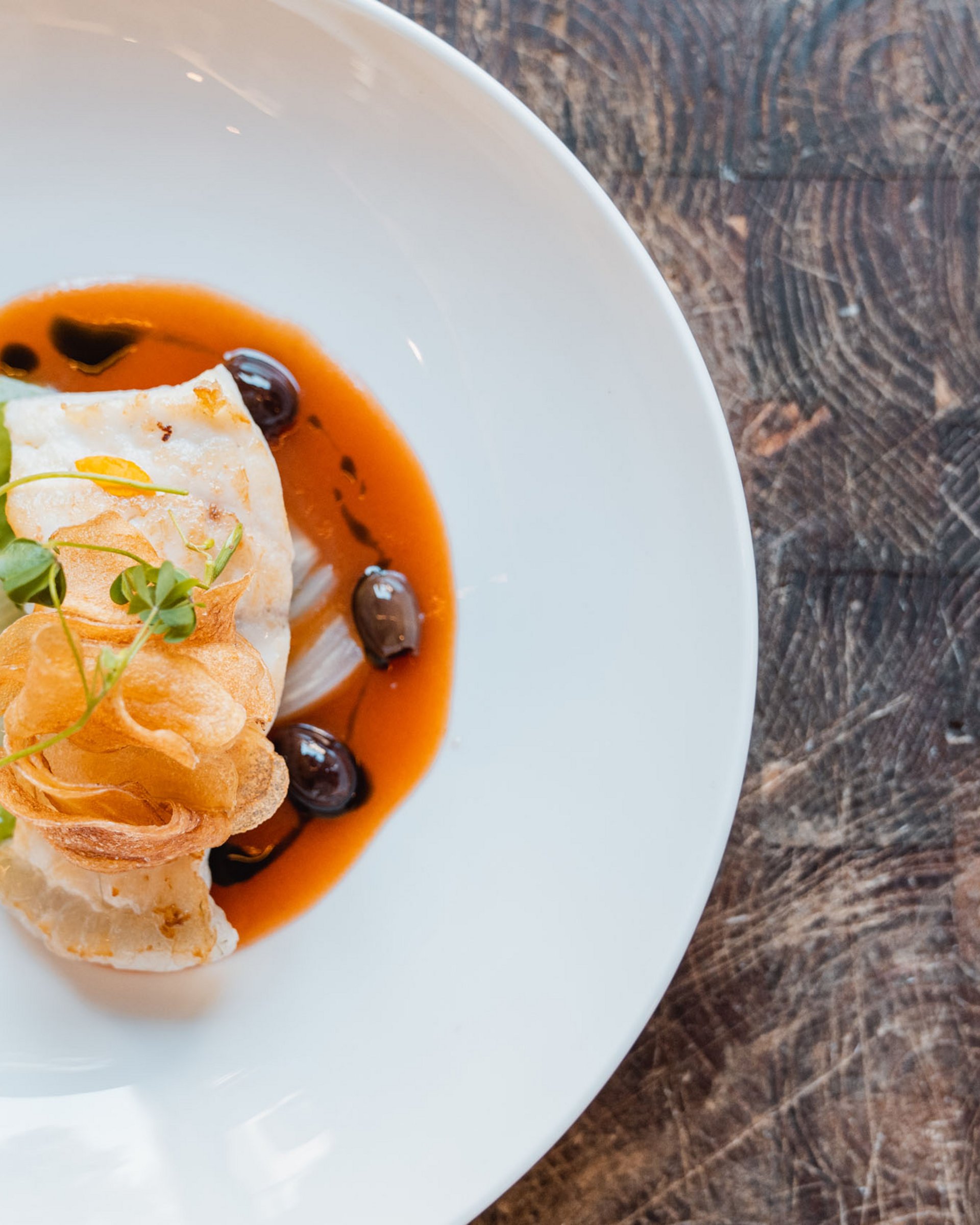 Artfully plated fish dish with green and red sauce on a white plate