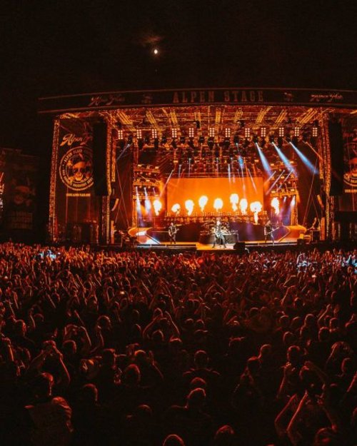 Großes Konzert mit Feuer- und Lichtshow auf der Alpenbühne vor einer jubelnden Menschenmenge nachts