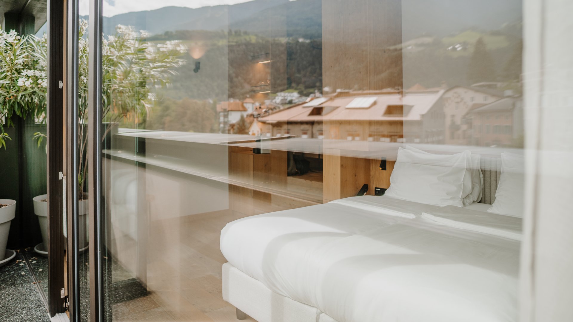 View through glass of a bright bed in a room with mountain view