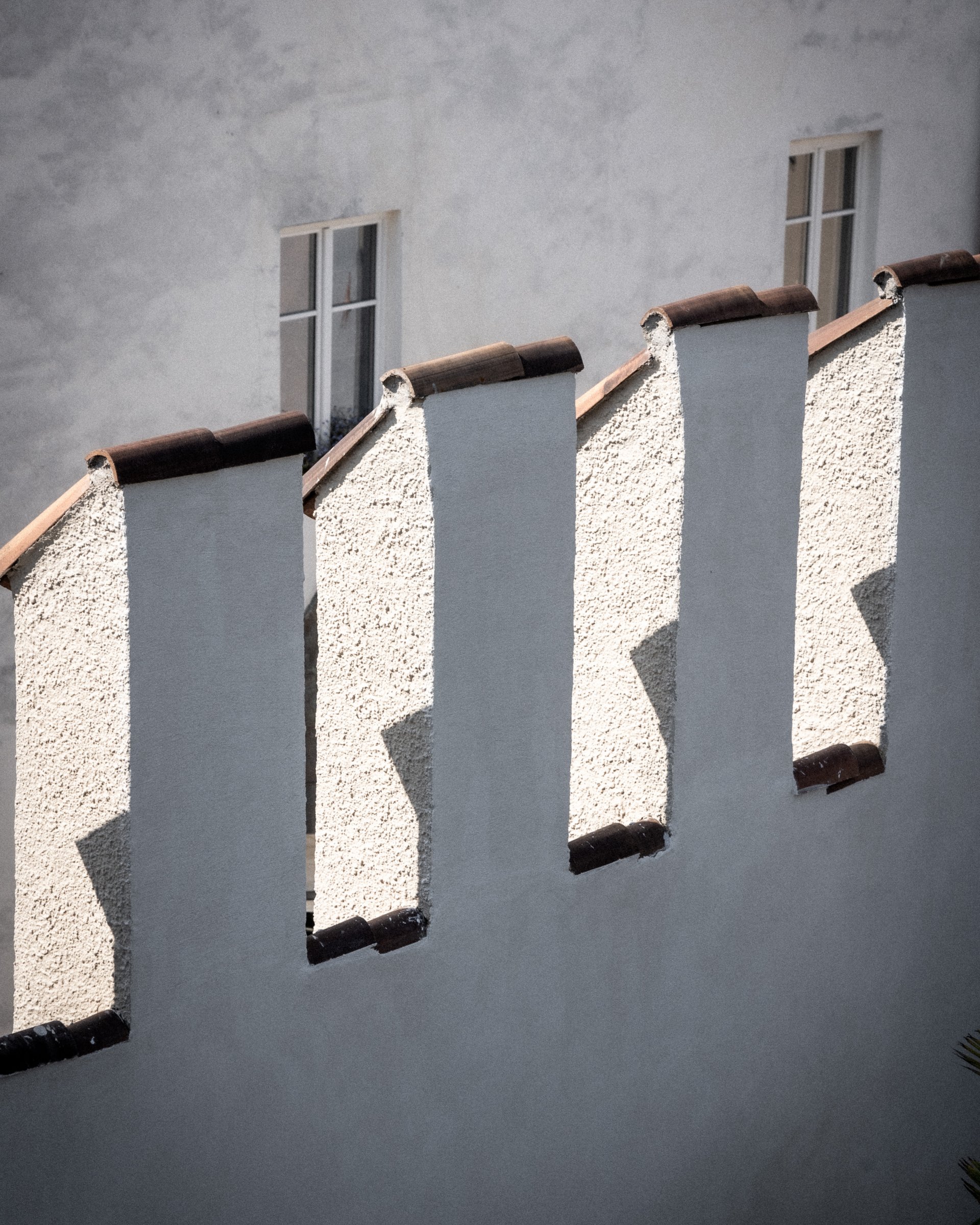 Mauermauer mit vier schmalen Öffnungen und zwei Fenstern im Hintergrund