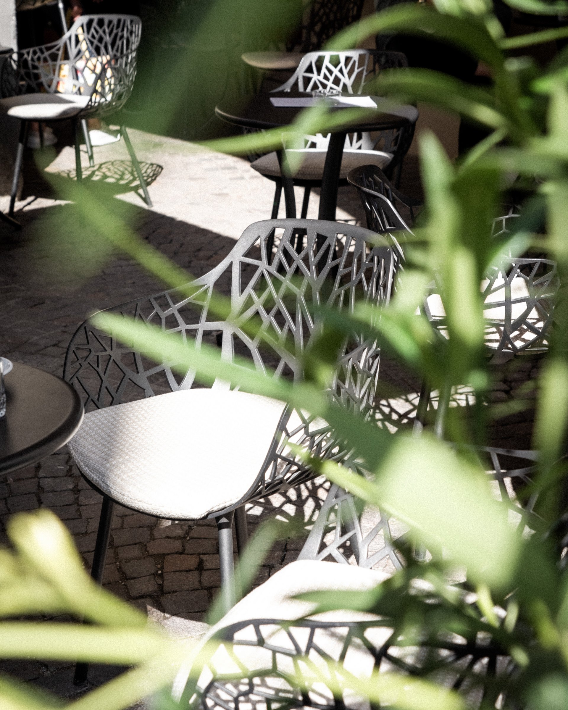 Moderne Außenstühle mit filigranem Design und hellem Sitzpolster im Freisitz