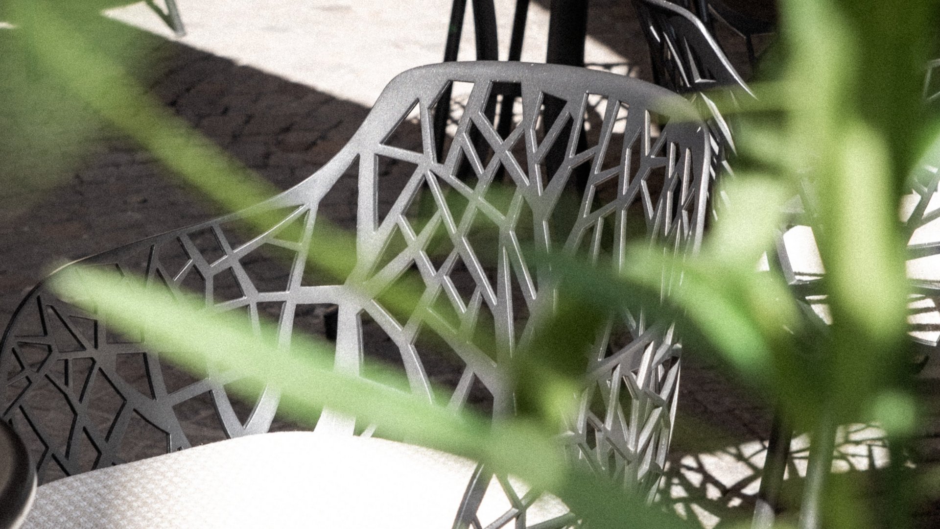 Modern outdoor chairs with intricate design and light cushions in a courtyard