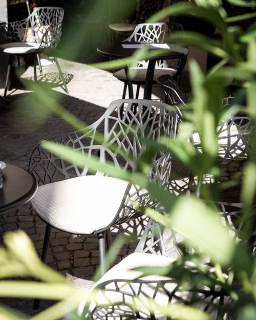 Modern outdoor chairs with intricate design and light cushions in a courtyard
