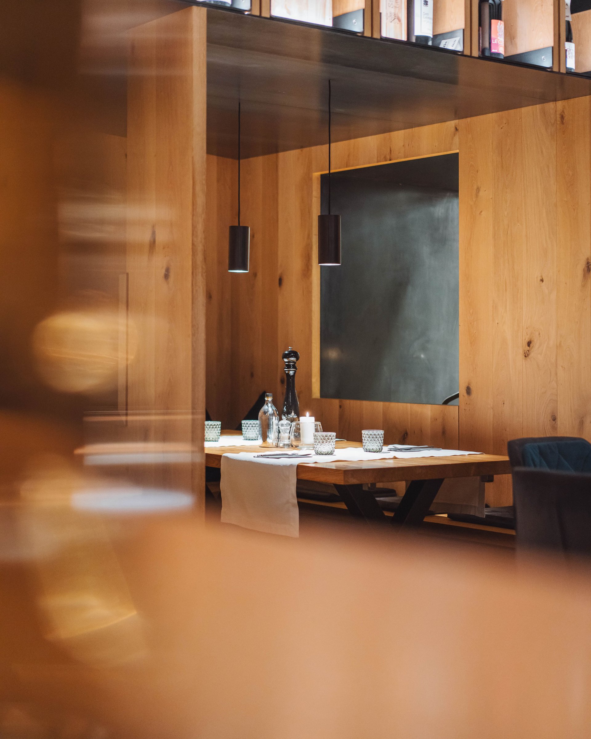 Cozy wooden table in modern restaurant with wine shelf above