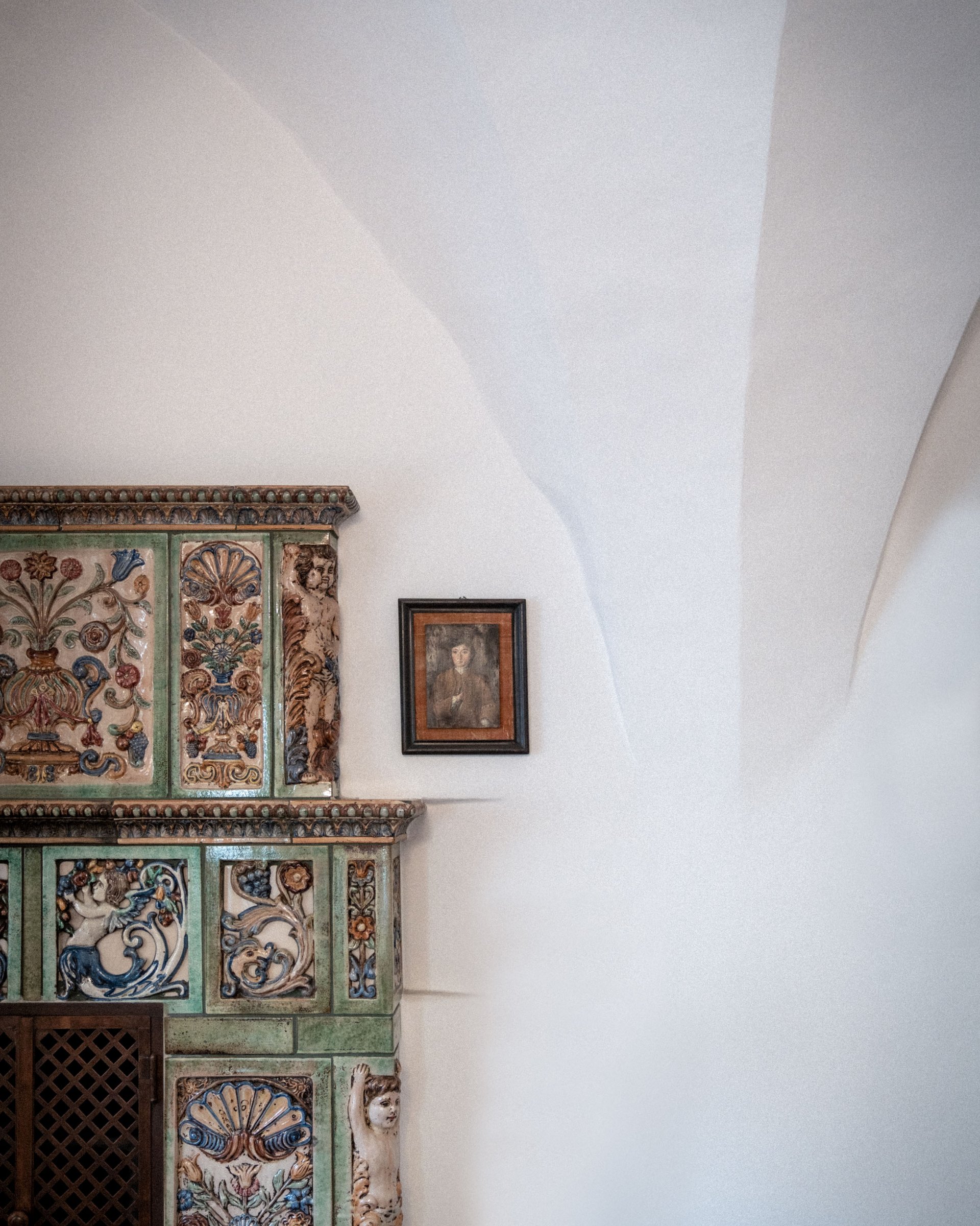 Ornate green tiled wall and small portrait on white wall