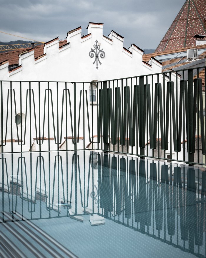 Reflection of railing on glass surface with historic building in the background