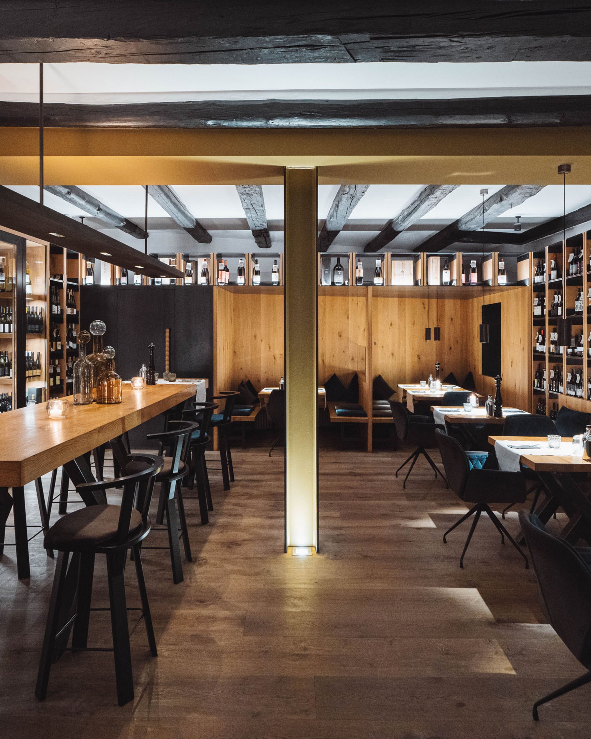 Cozy restaurant with wooden tables and wine shelves lining the walls