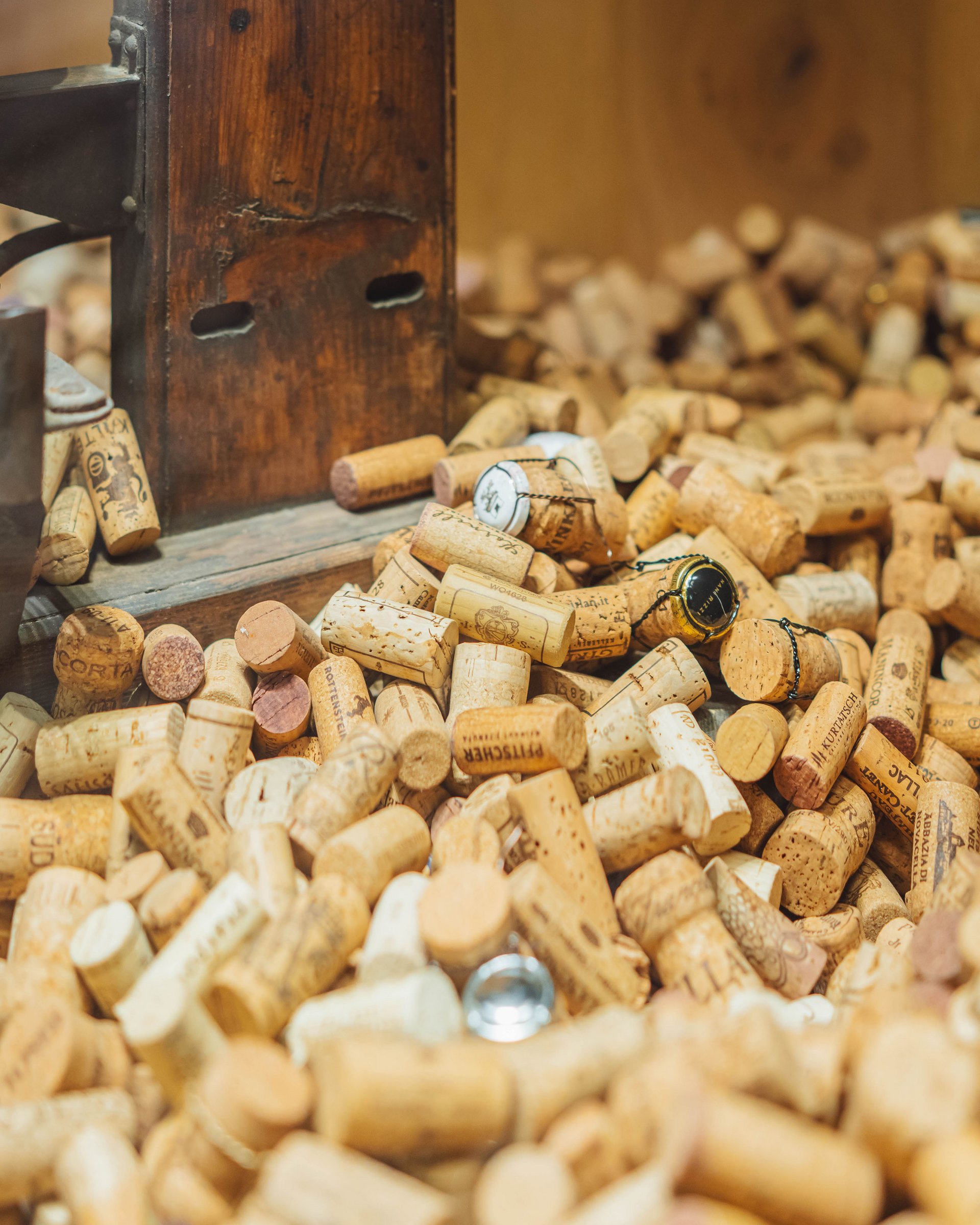 Many wine corks scattered in front of a wooden board