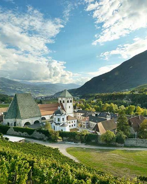 Kloster in grüner Landschaft und Bergen bei wolkigem Himmel