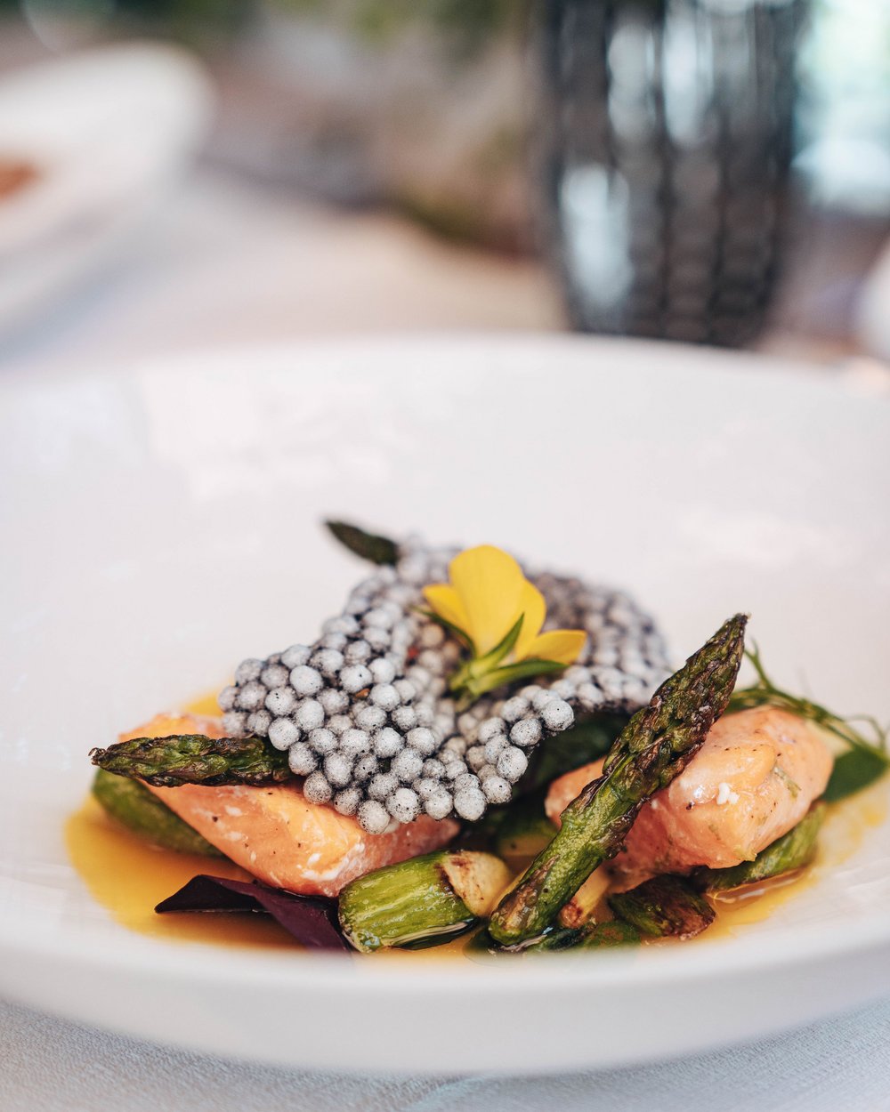Gourmet dish with salmon, asparagus and edible flower on a white plate