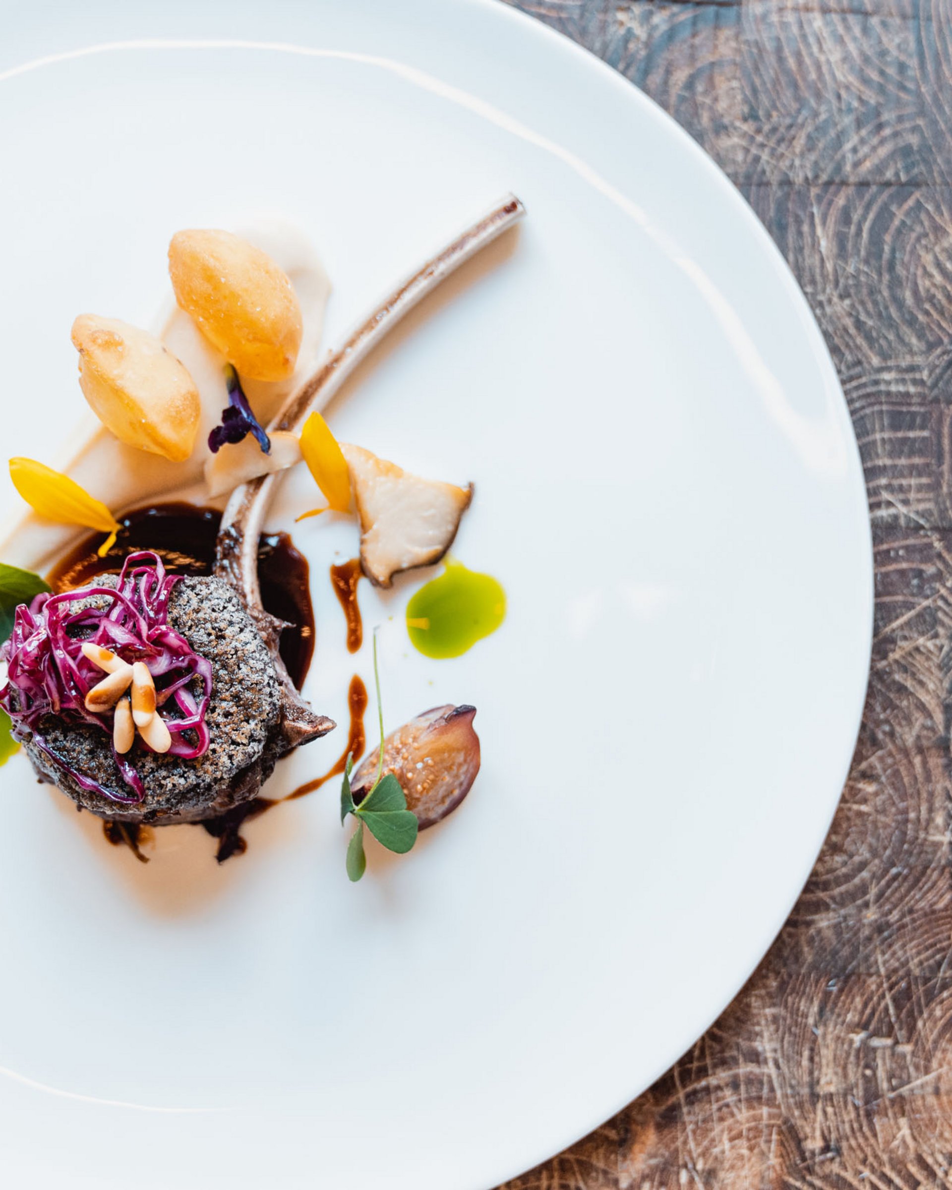 Elegantly plated gourmet lamb chop with colorful garnishes on a white plate