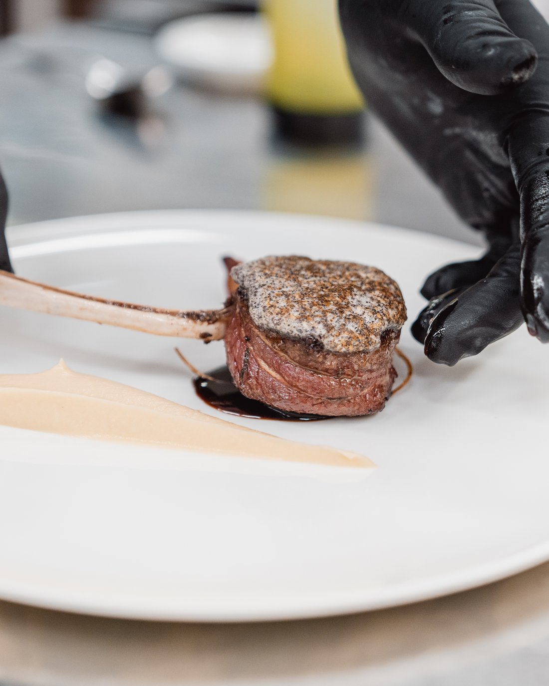 Gourmetgericht mit Fleisch und Creme wird auf weißem Teller angerichtet