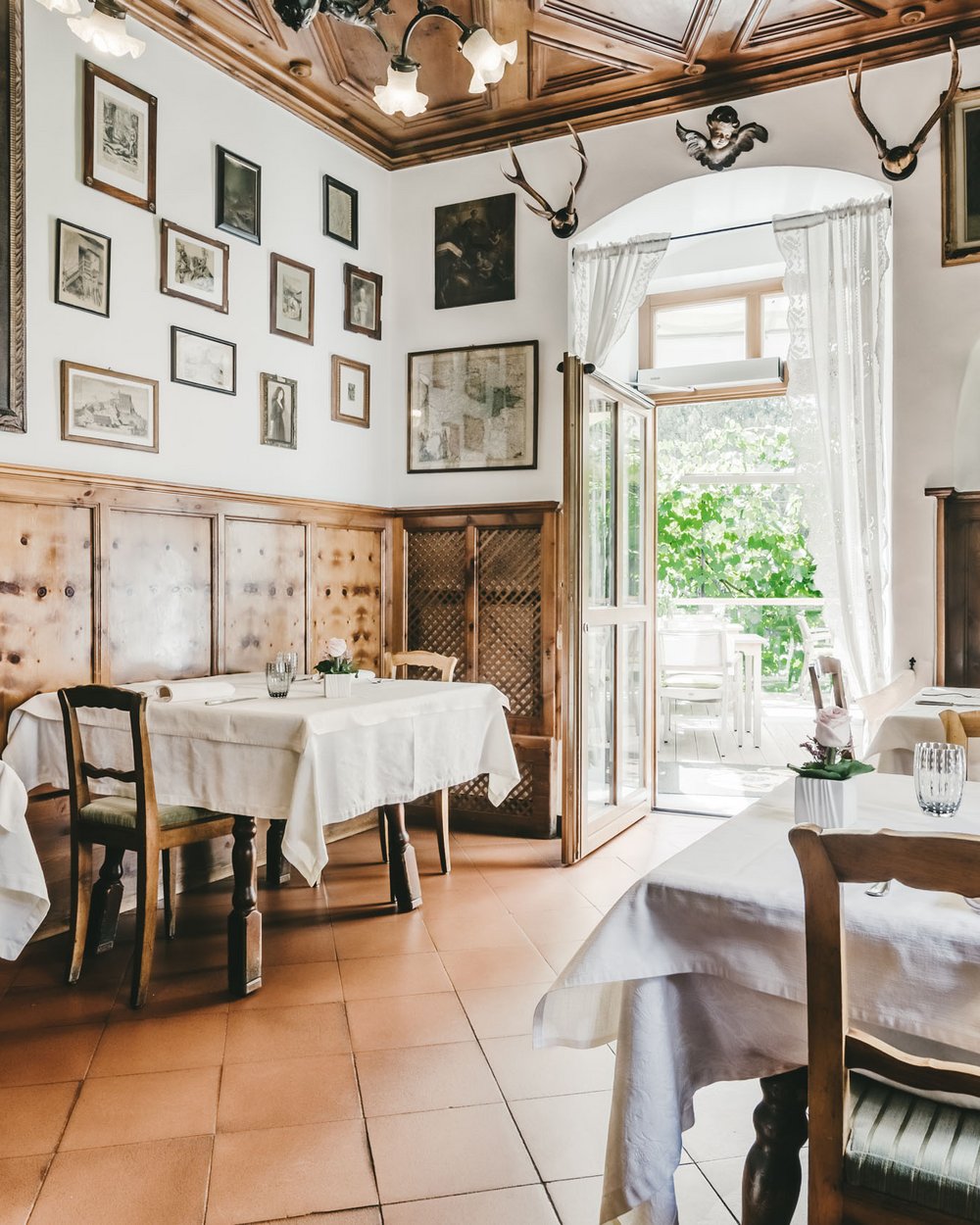Cozy restaurant with wooden furniture, white tablecloths, and artwork on the walls