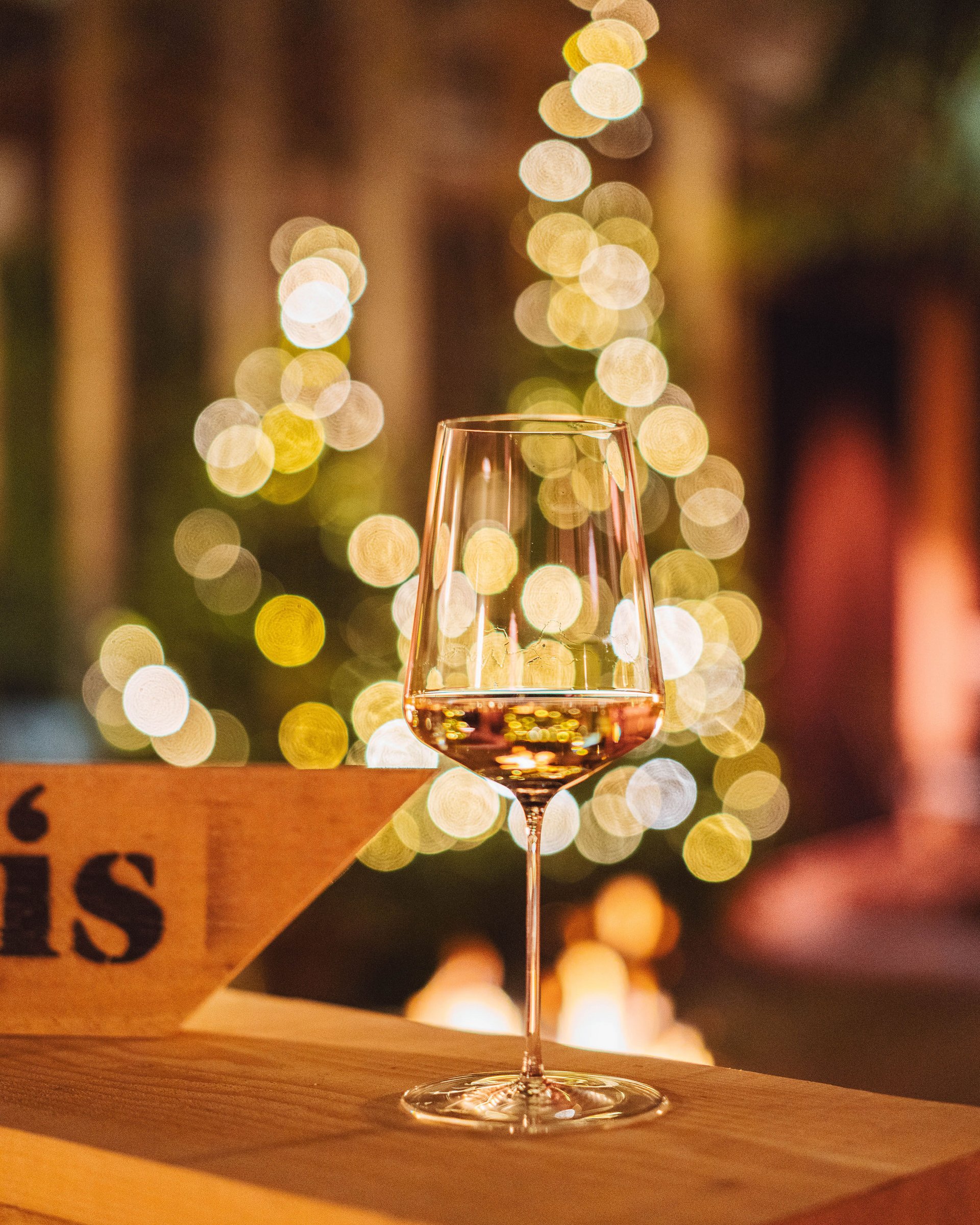 Glass of white wine with blurred string lights in background