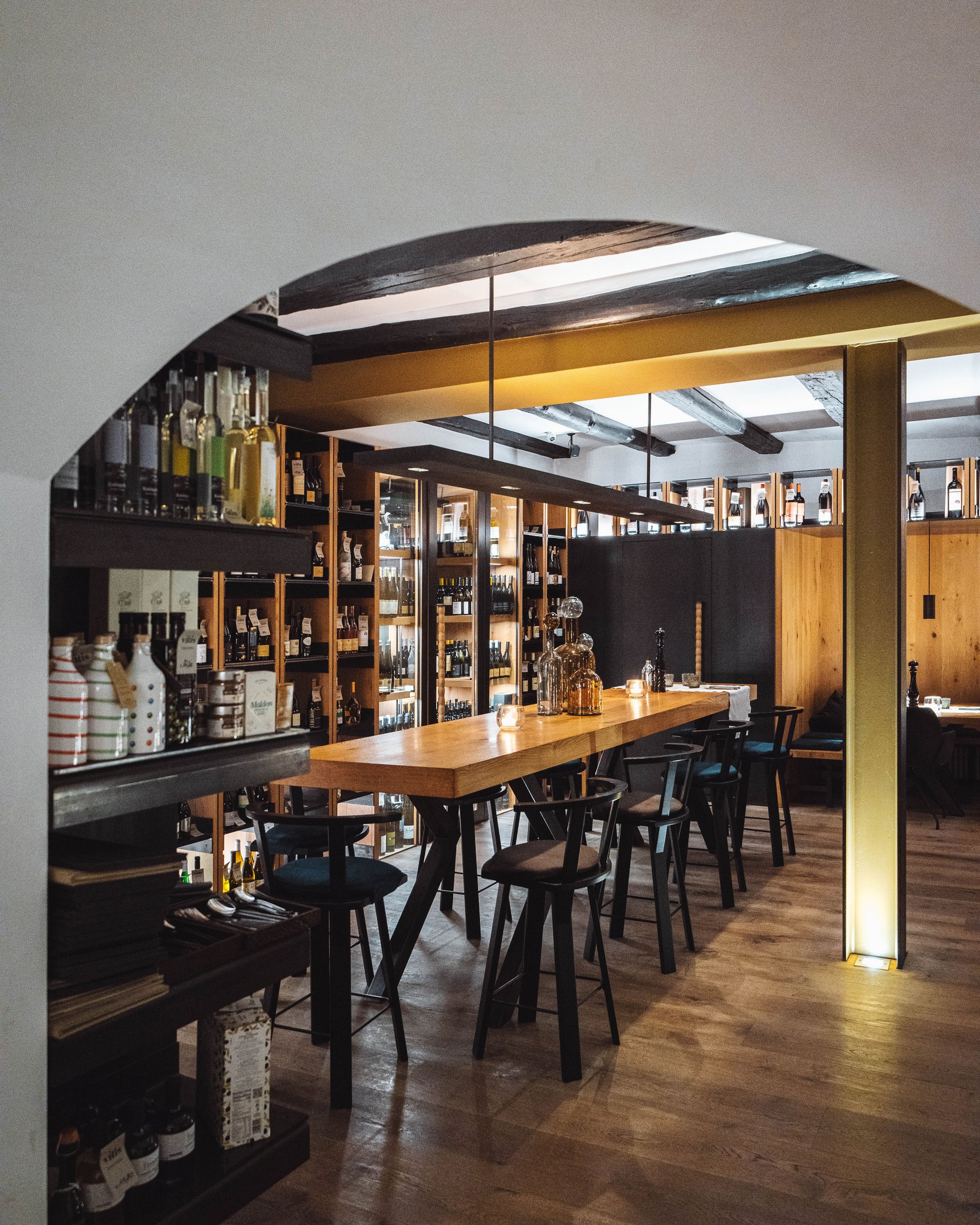 Cozy bar area with wooden counter, chairs, and shelves filled with bottles