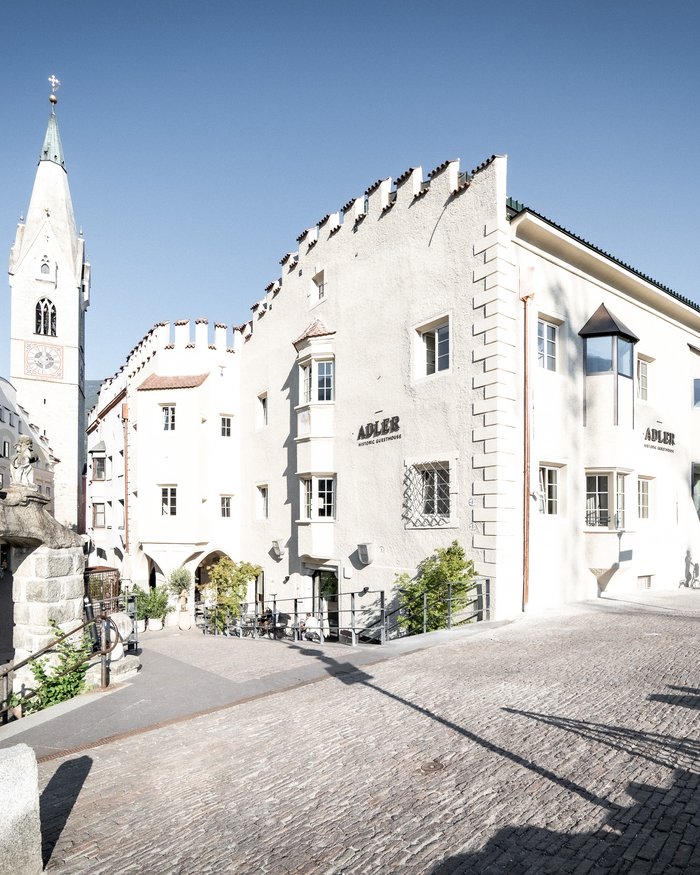 Historisches Gebäude Adler mit Turm und Steinbrücke an sonniger Straße