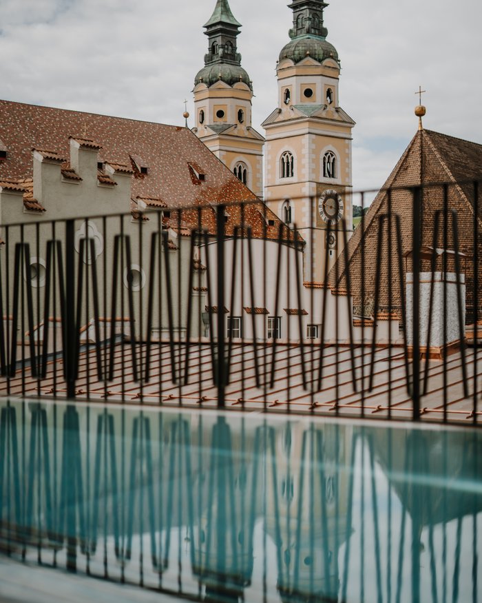 View of church towers and rooftops behind metal railing with reflection