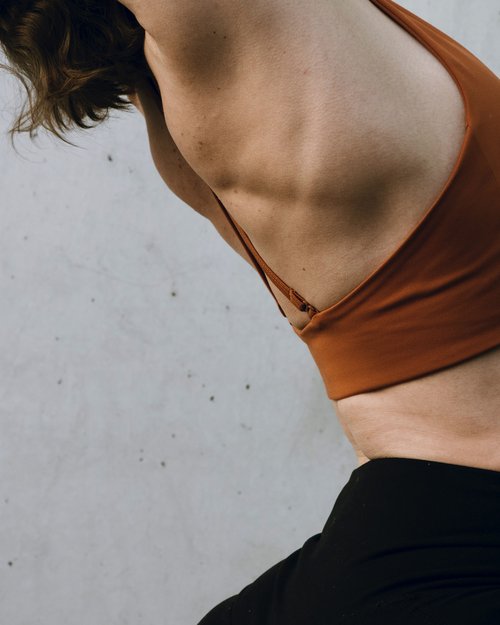 Woman in sportswear stretching in front of gray wall