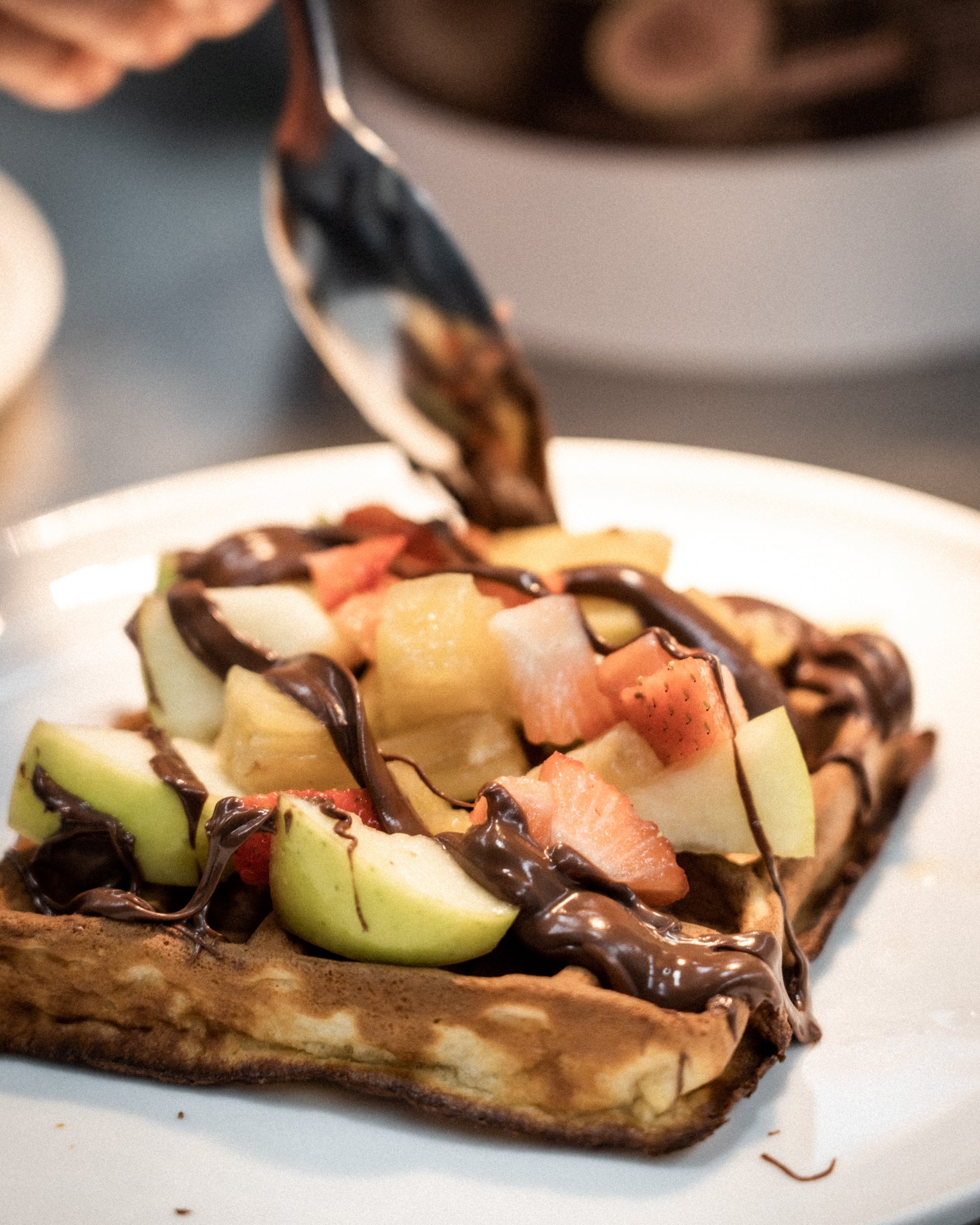 Waffel mit frischem Obst und Schokoladensoße auf einem weißen Teller