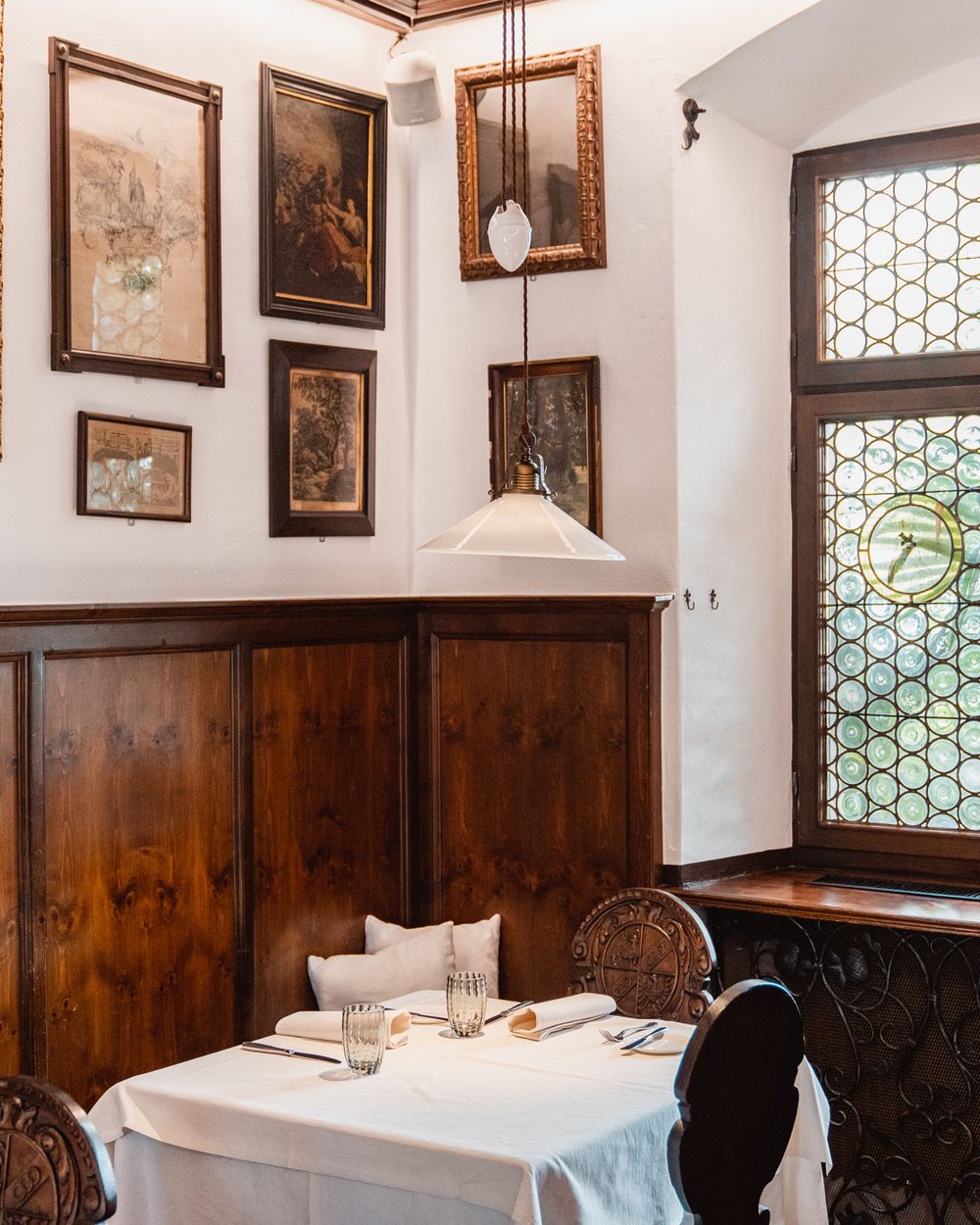 Gemütlicher Essbereich mit Holzwänden, Kunst und buntem Glasfenster