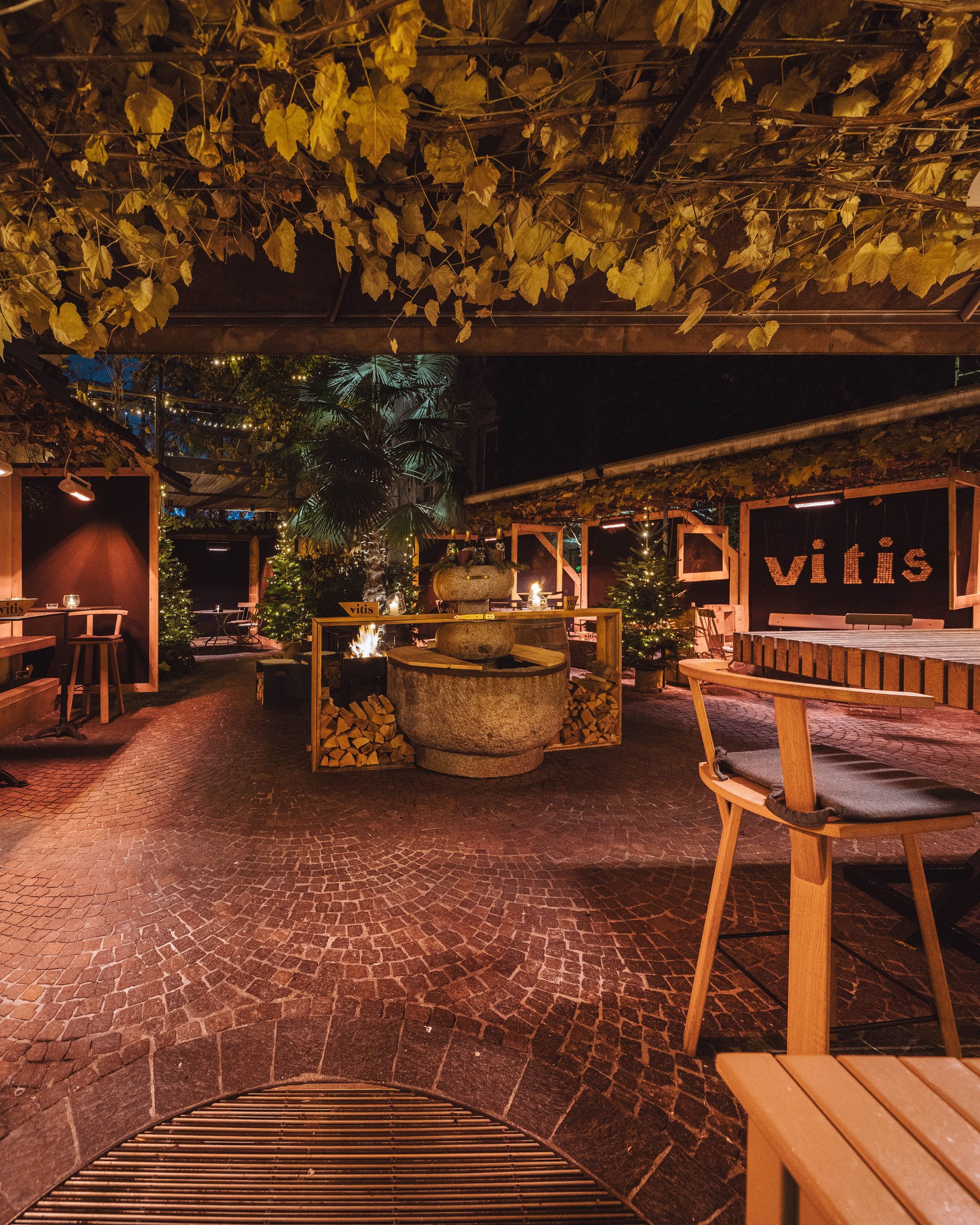 Cozy outdoor bar with wooden ceiling and fire pit at night