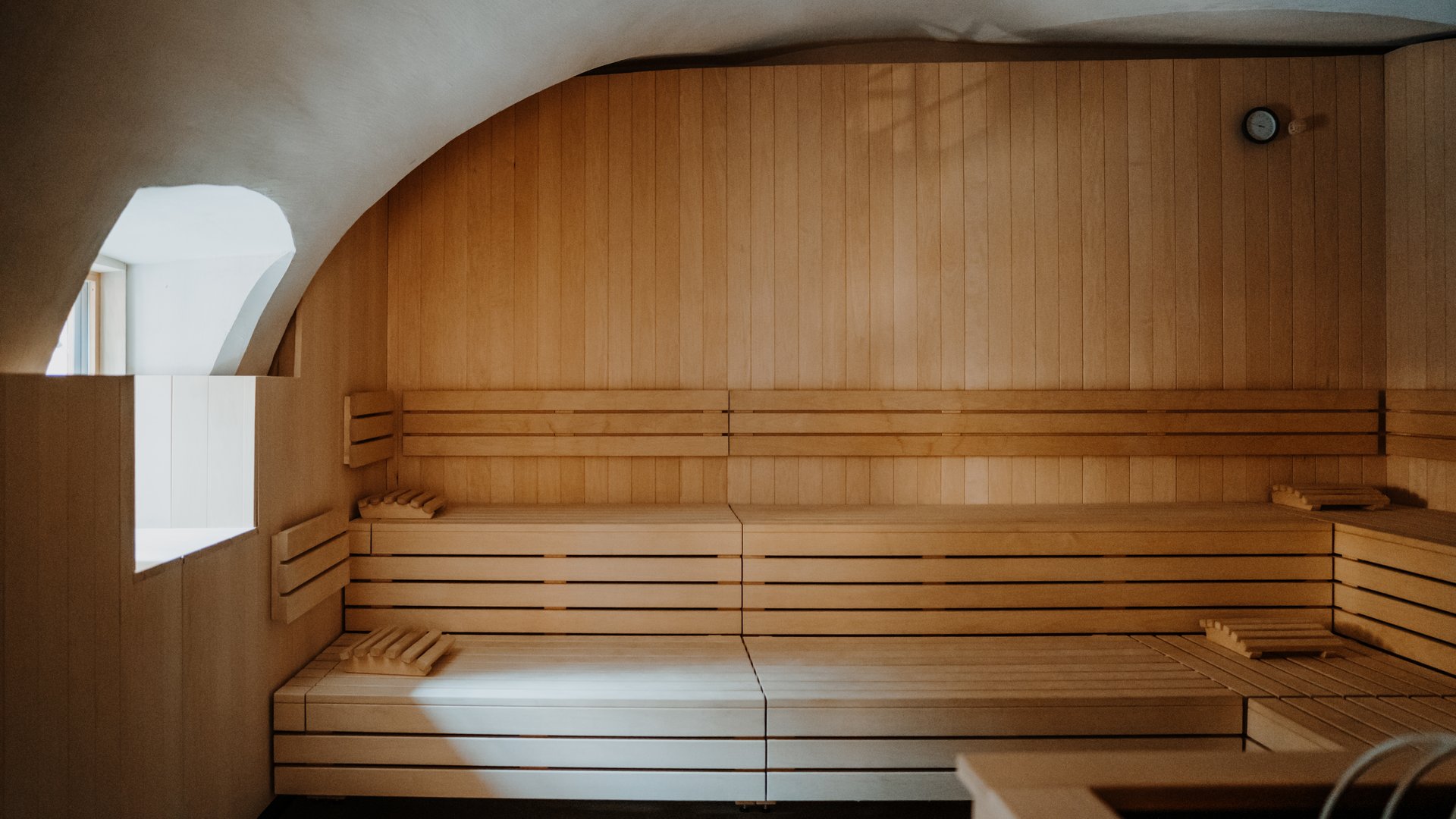 Empty sauna room with wooden benches and light from window
