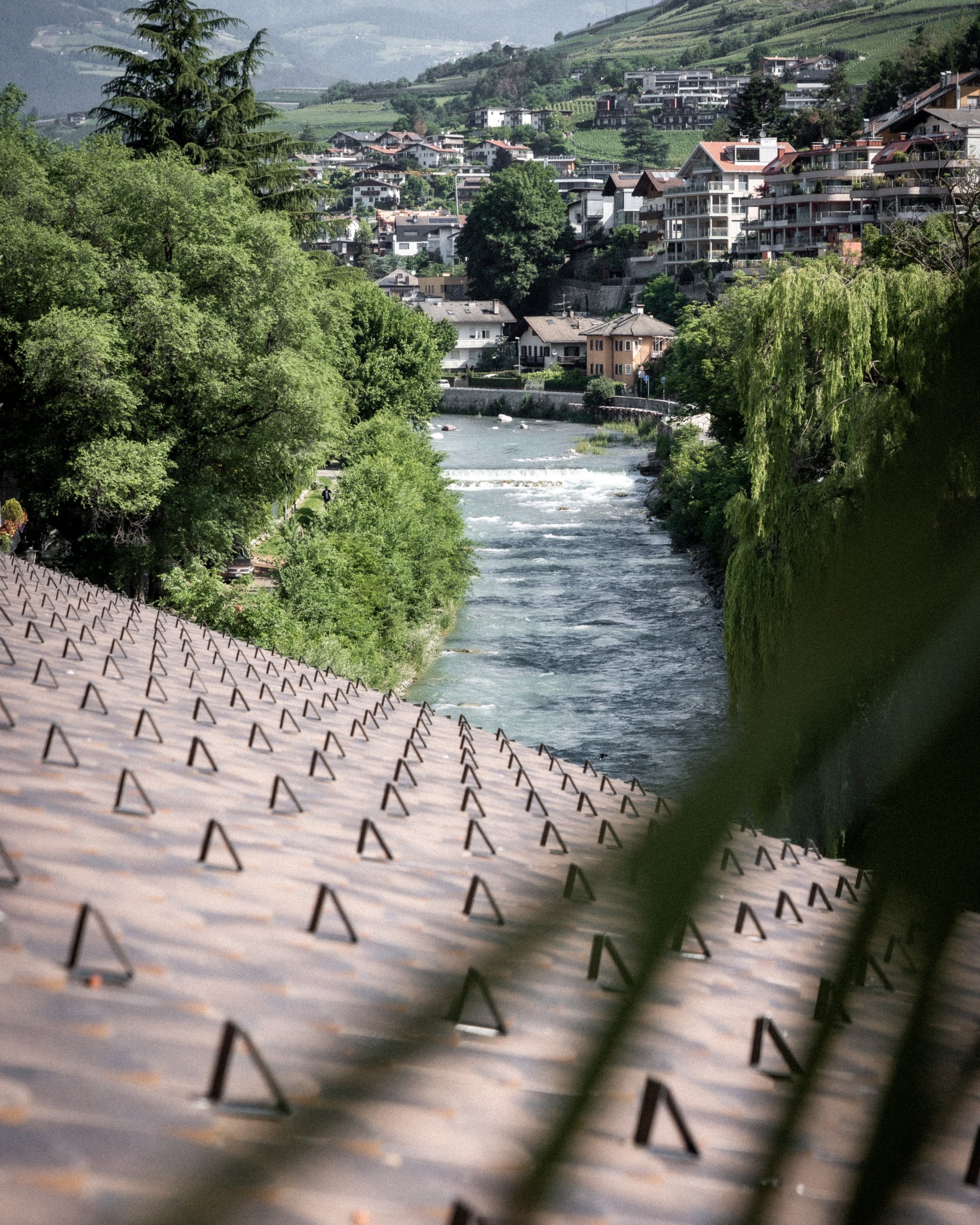 Fluss fließt durch grüne Landschaft mit Häusern und Bergen im Hintergrund