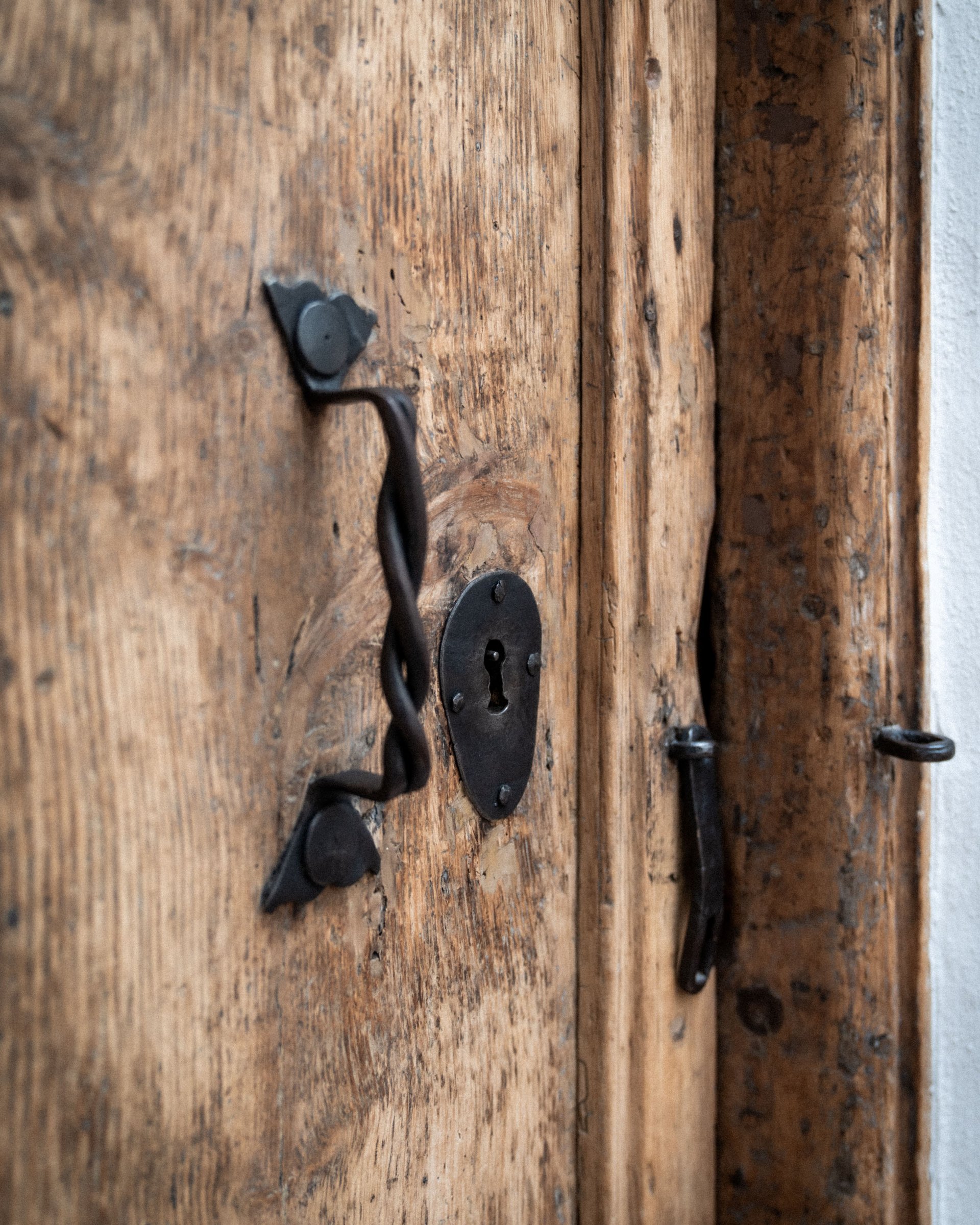 Close-up of an antique wooden door with twisted metal handle and keyhole