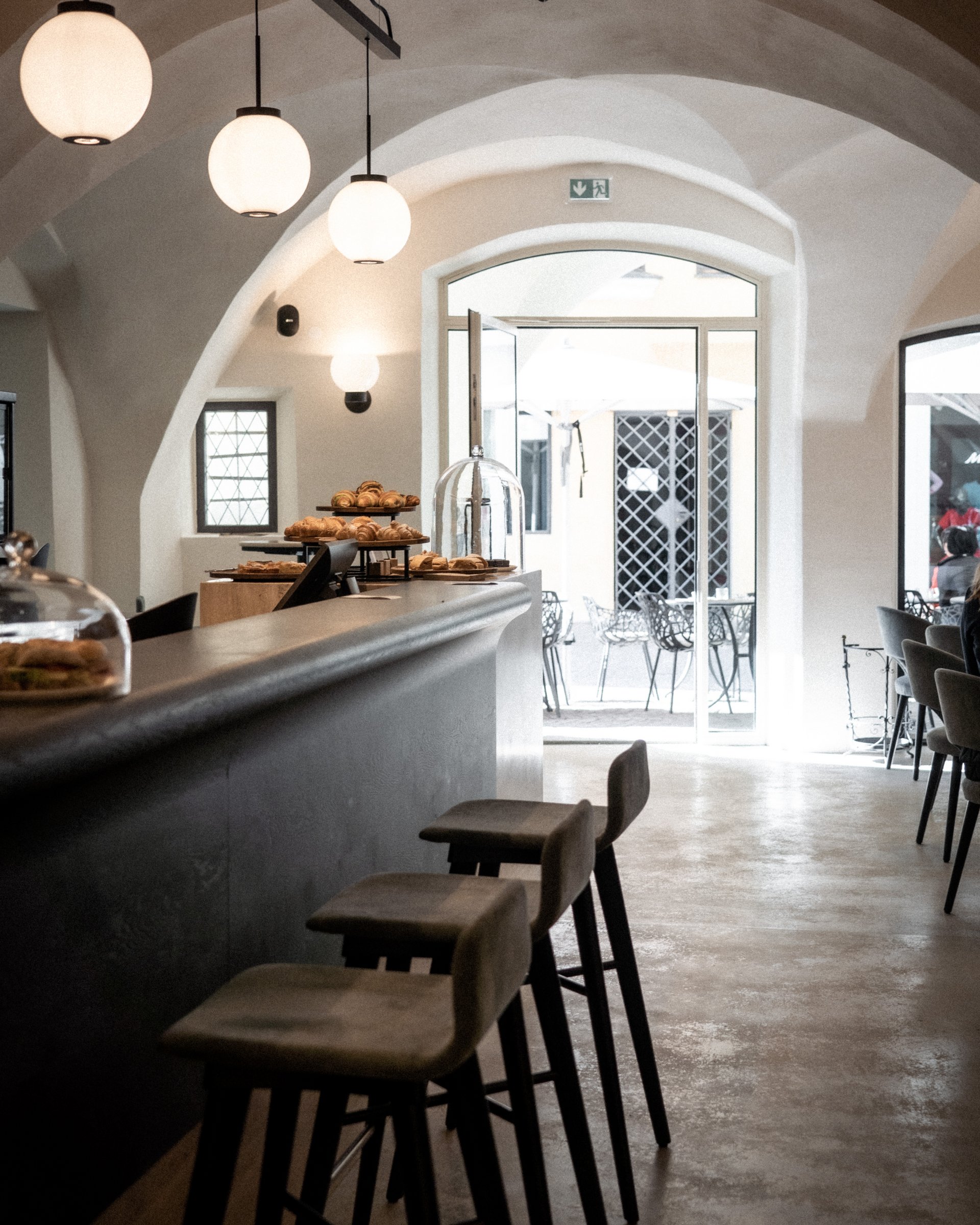 Innenansicht eines Cafés mit Bartresen, Hockern und Gebäck an der Theke