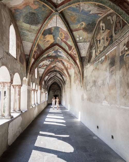 Historischer Kreuzgang mit bemalten Gewölbedecken und zwei Personen im Licht