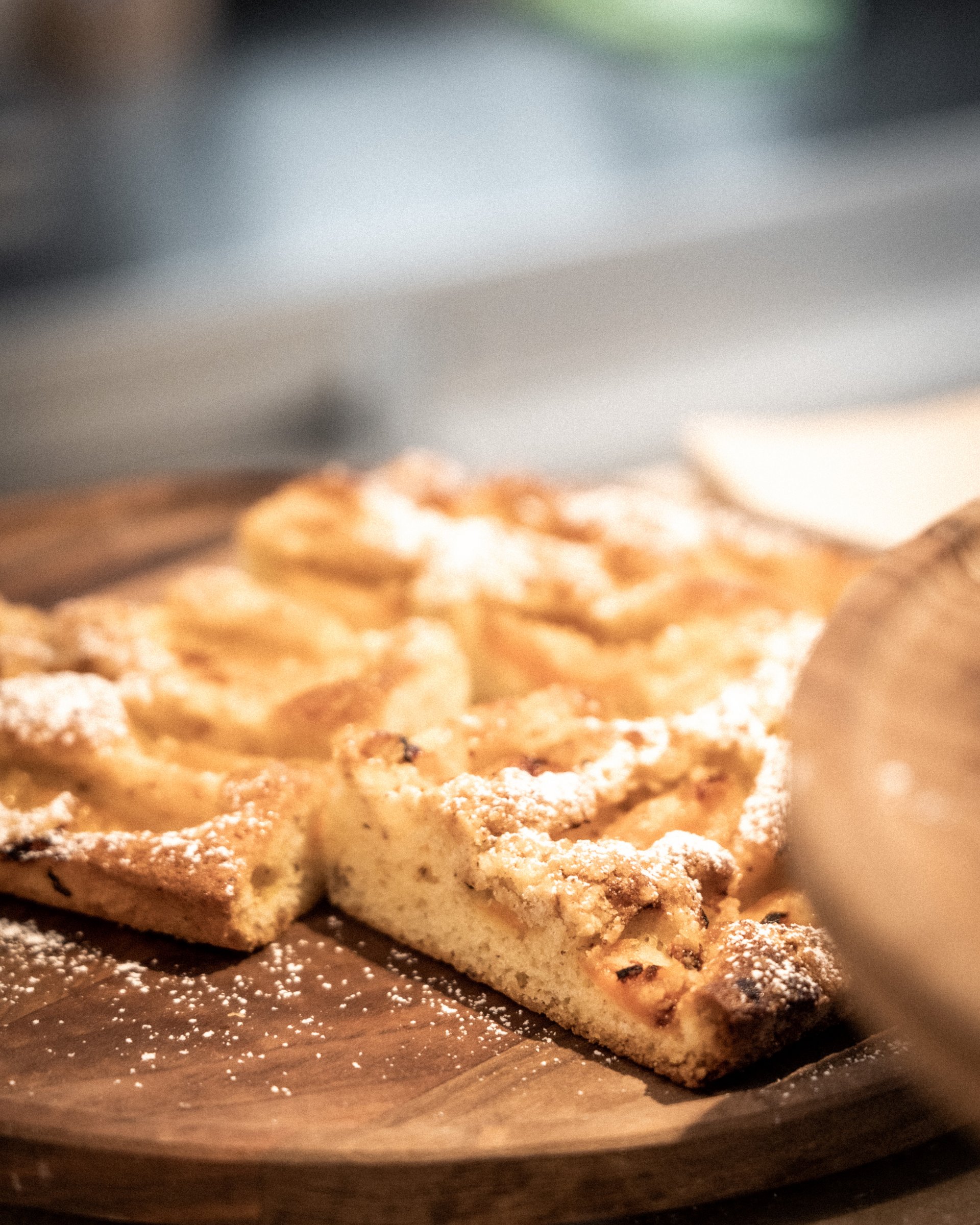 Scheiben von Apfelkuchen mit Puderzucker auf einem Holzbrett