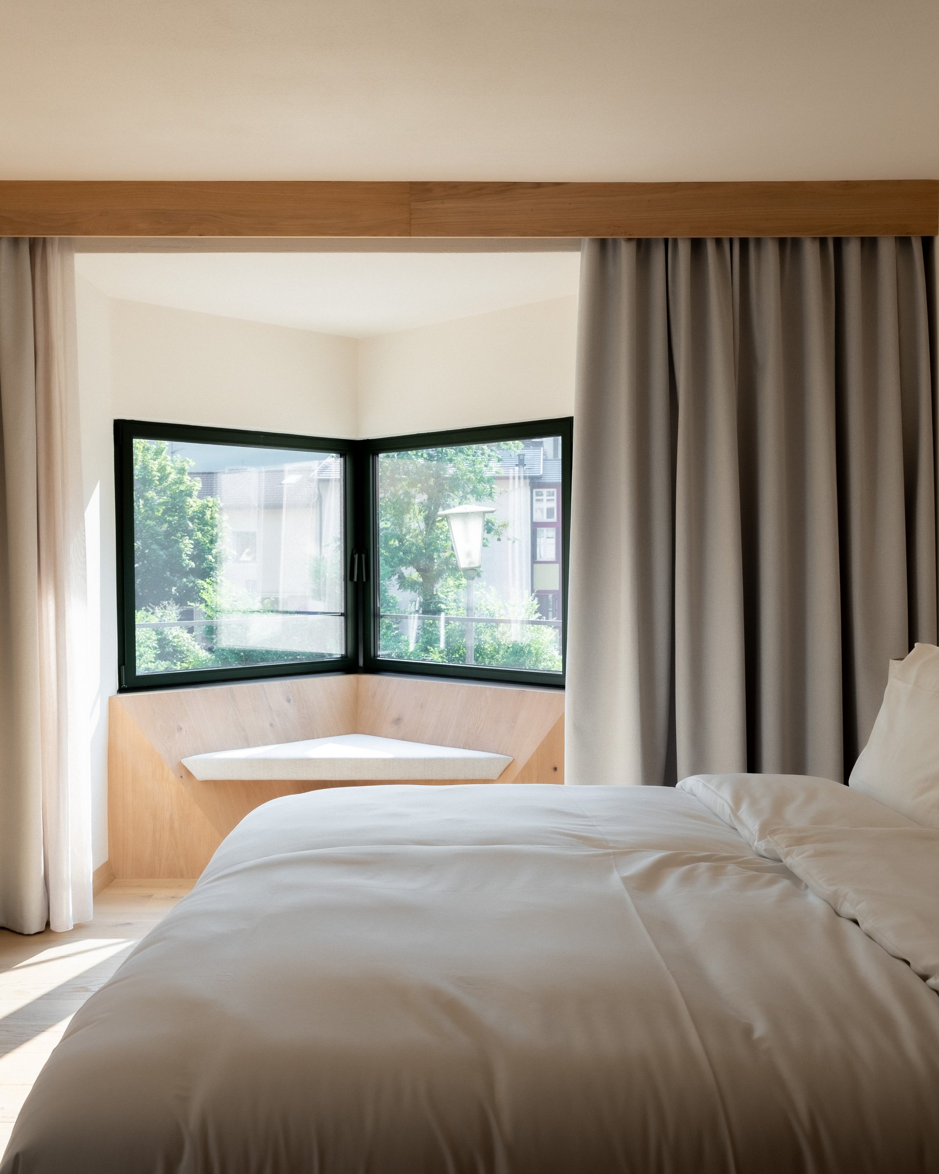 Modernes Schlafzimmer mit großem Fenster und Sitzbereich in neutralen Farben