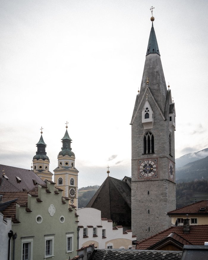Clock tower and surrounding buildings in a mountain town under a cloudy sky